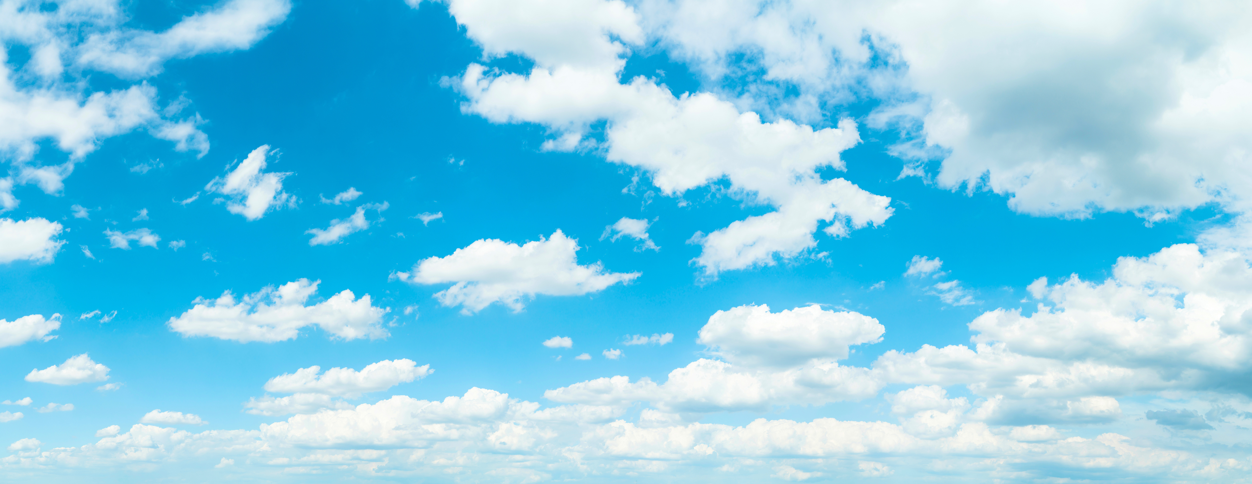 Lucht vol witte, pluizige wolken. De lucht is helder, helderblauw.