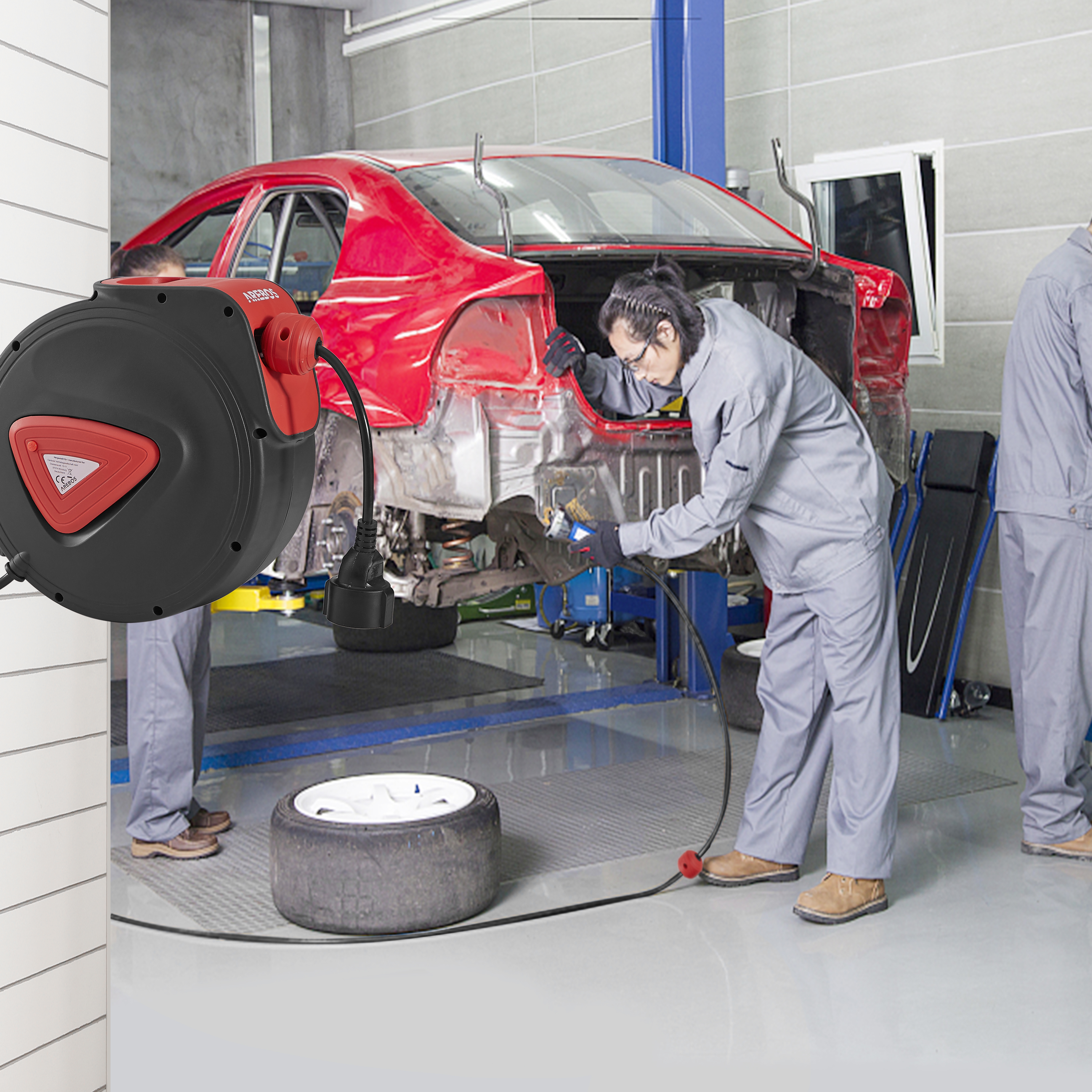 Mechaniker in Garage arbeitet an rotem Auto, Schlauchaufroller an Wand montiert.