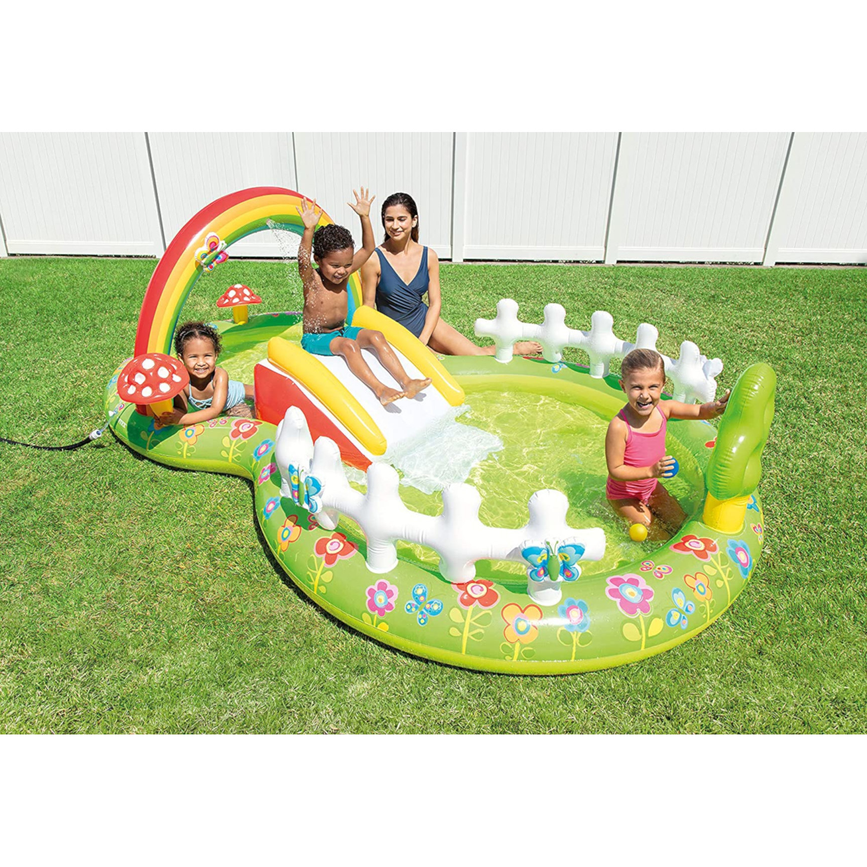 Bambini in piscina da giardino con scivolo, arcobaleno e decorazioni a fungo.