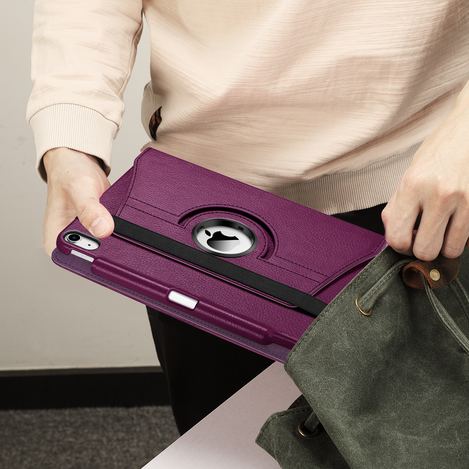 Eine Person, die eine lila Tablethülle mit einem Stift in eine grüne Tasche steckt.