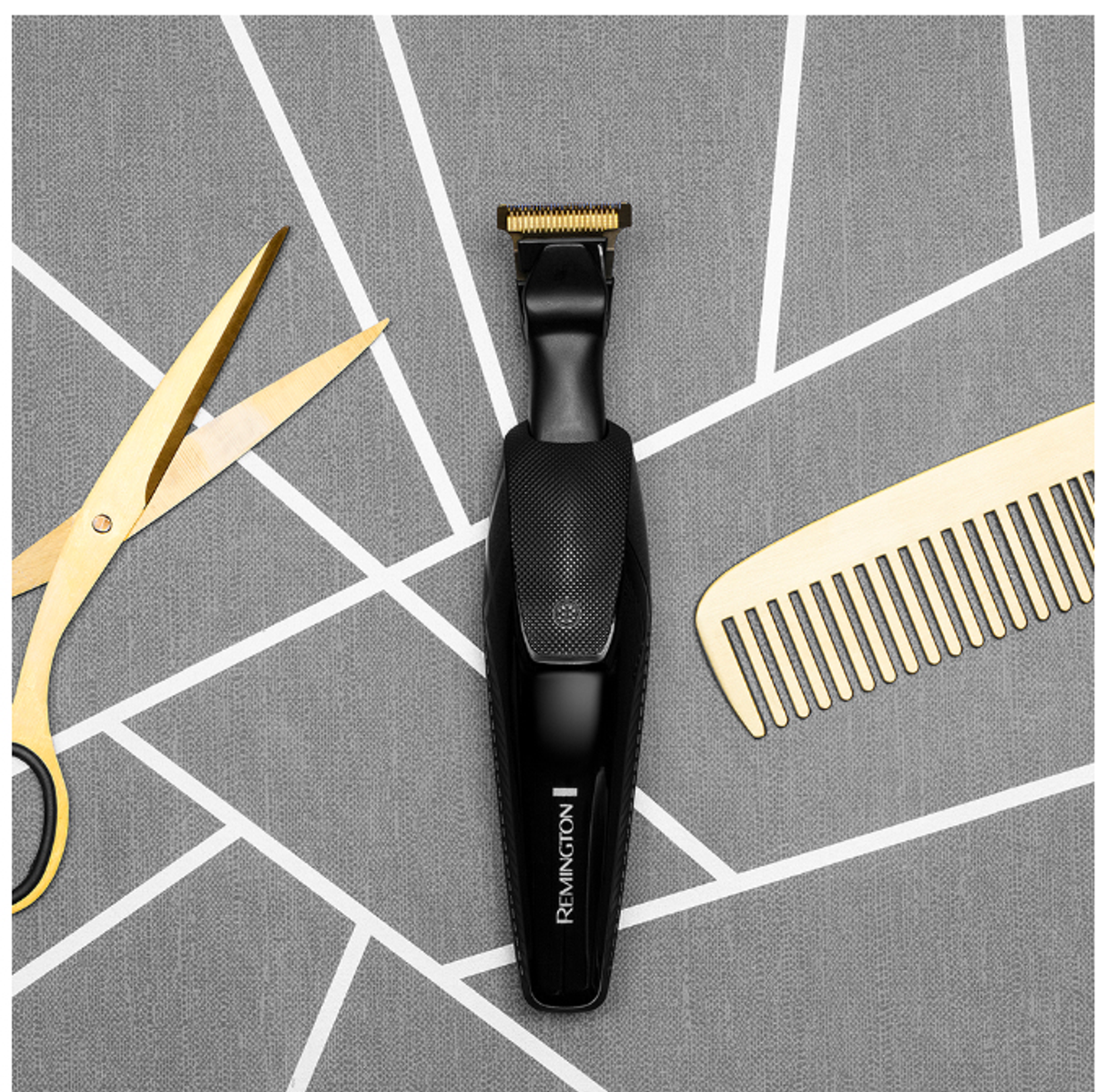 Czarny trymer, złote nożyczki i złoty grzebień na szarej, wzorzystej powierzchni.