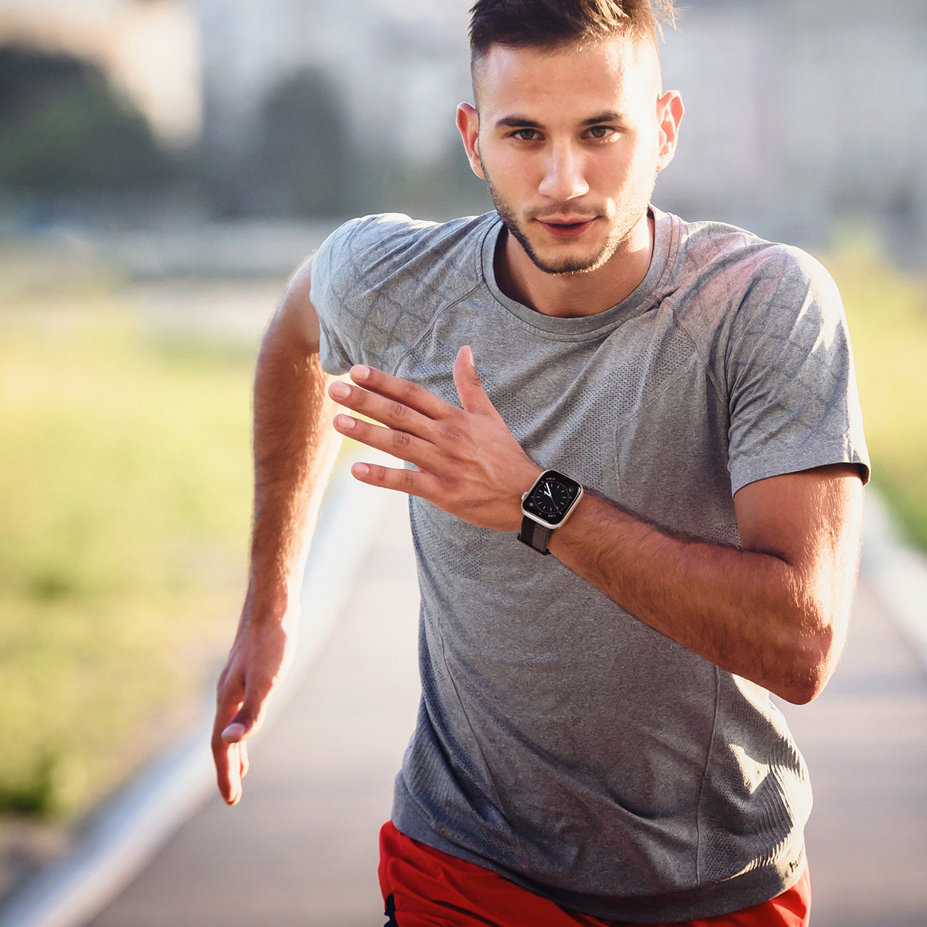 Ein Mann in grauem Hemd und roter Hose rennt auf die Kamera zu. Er trägt eine Smartwatch.