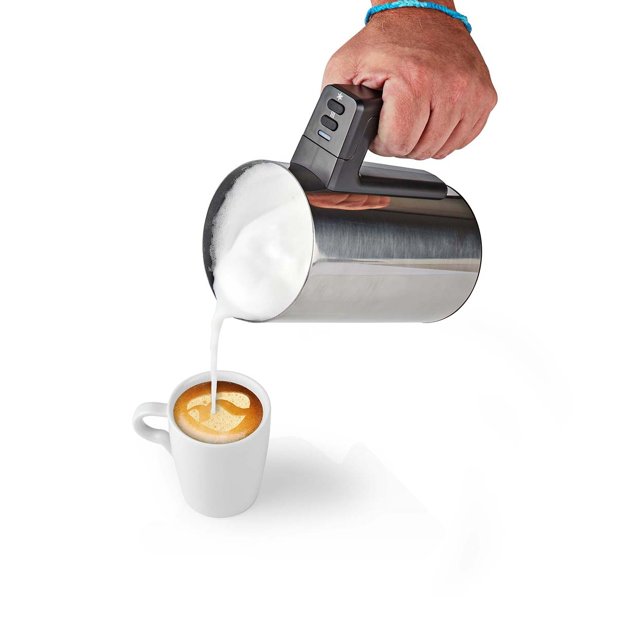 Una mano versa densa schiuma di latte bianca da una lattiera in metallo in una tazza di caffè.