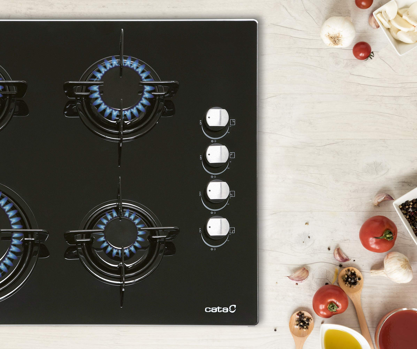 Czarna płyta grzewcza z niebieskimi płomieniami, otoczona składnikami na drewnie.