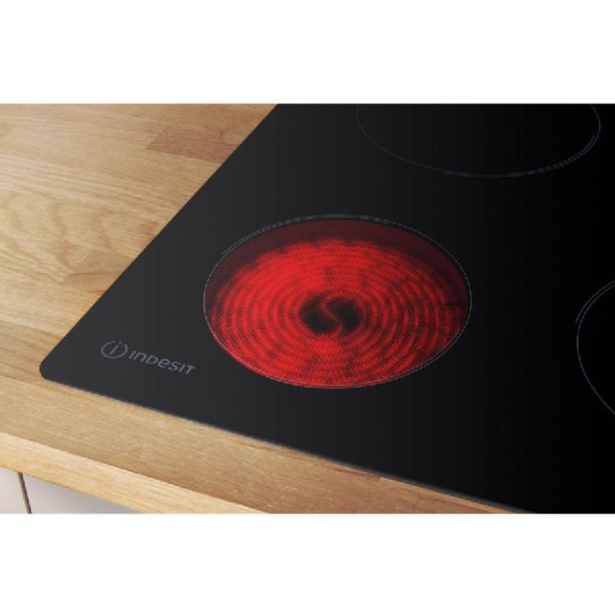 Una placa de inducción Indesit negra con un quemador rojo al rojo vivo.