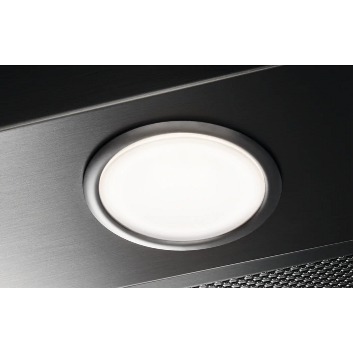 Primer plano de luz redonda iluminada sobre superficie metálica oscura.