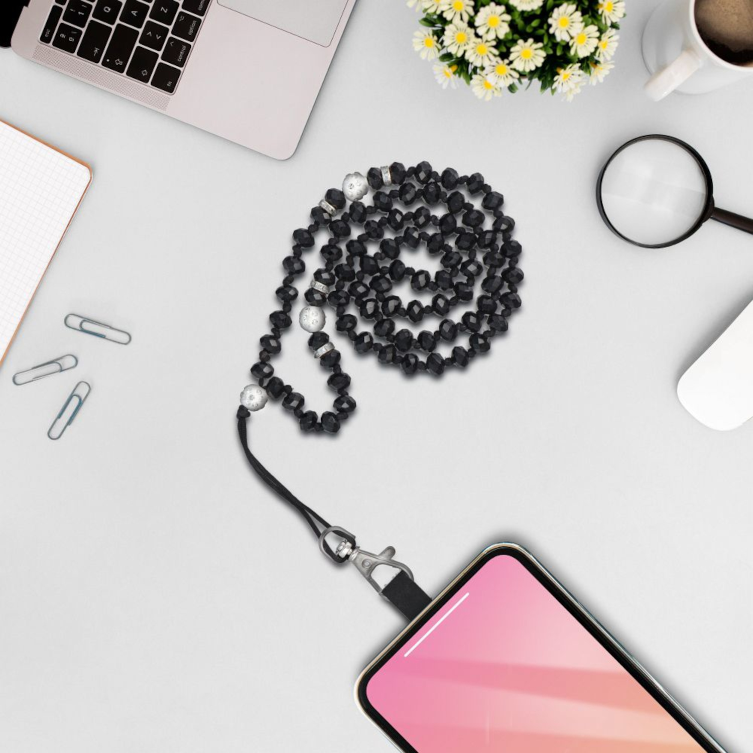 Schwarze Perlen-Handy-Kette mit Silberverschluss. Telefon und Zubehör auf weißer Oberfläche.