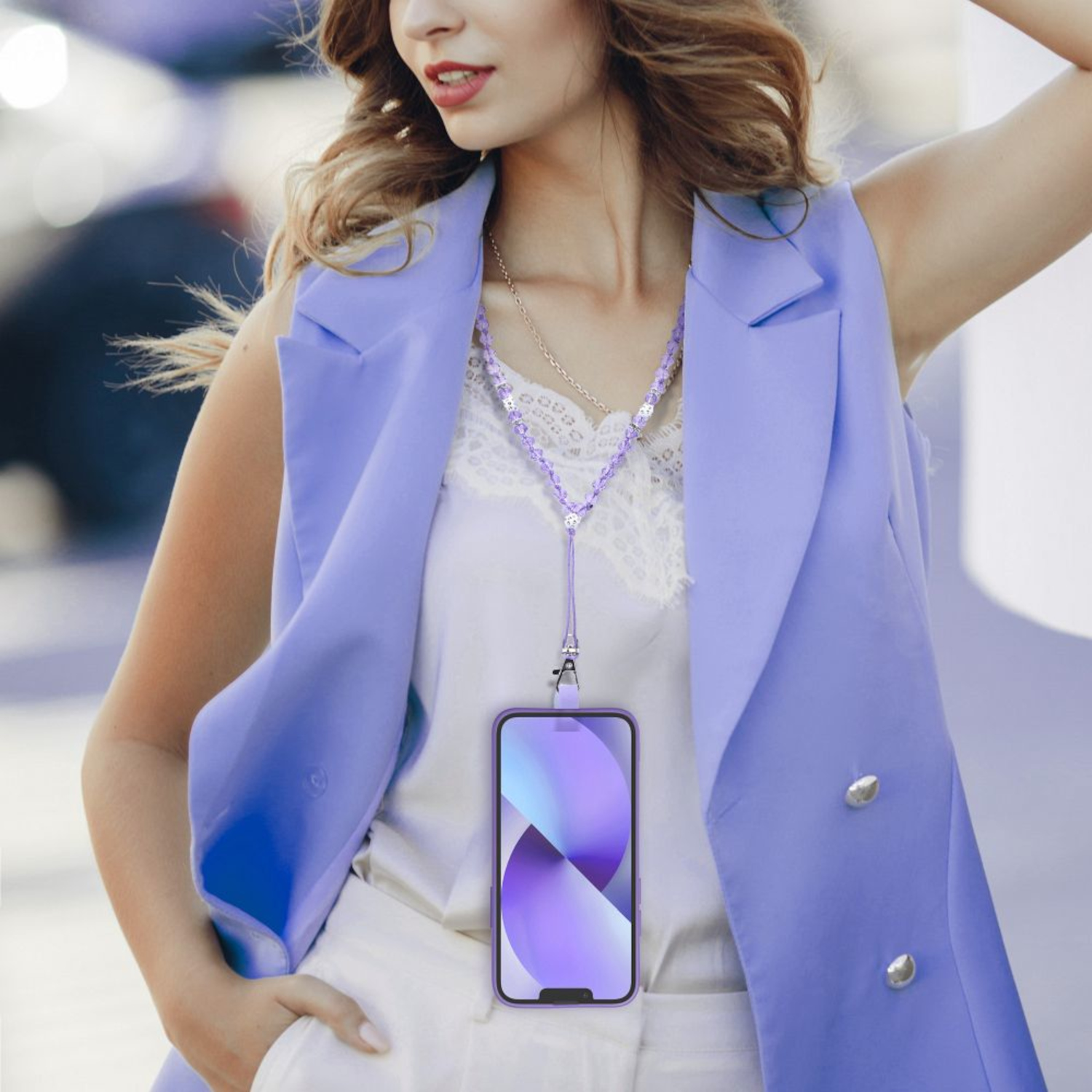 Frau in lila Weste mit Telefon. Telefon mit lila Hülle, weißem Oberteil, weißer Hose.