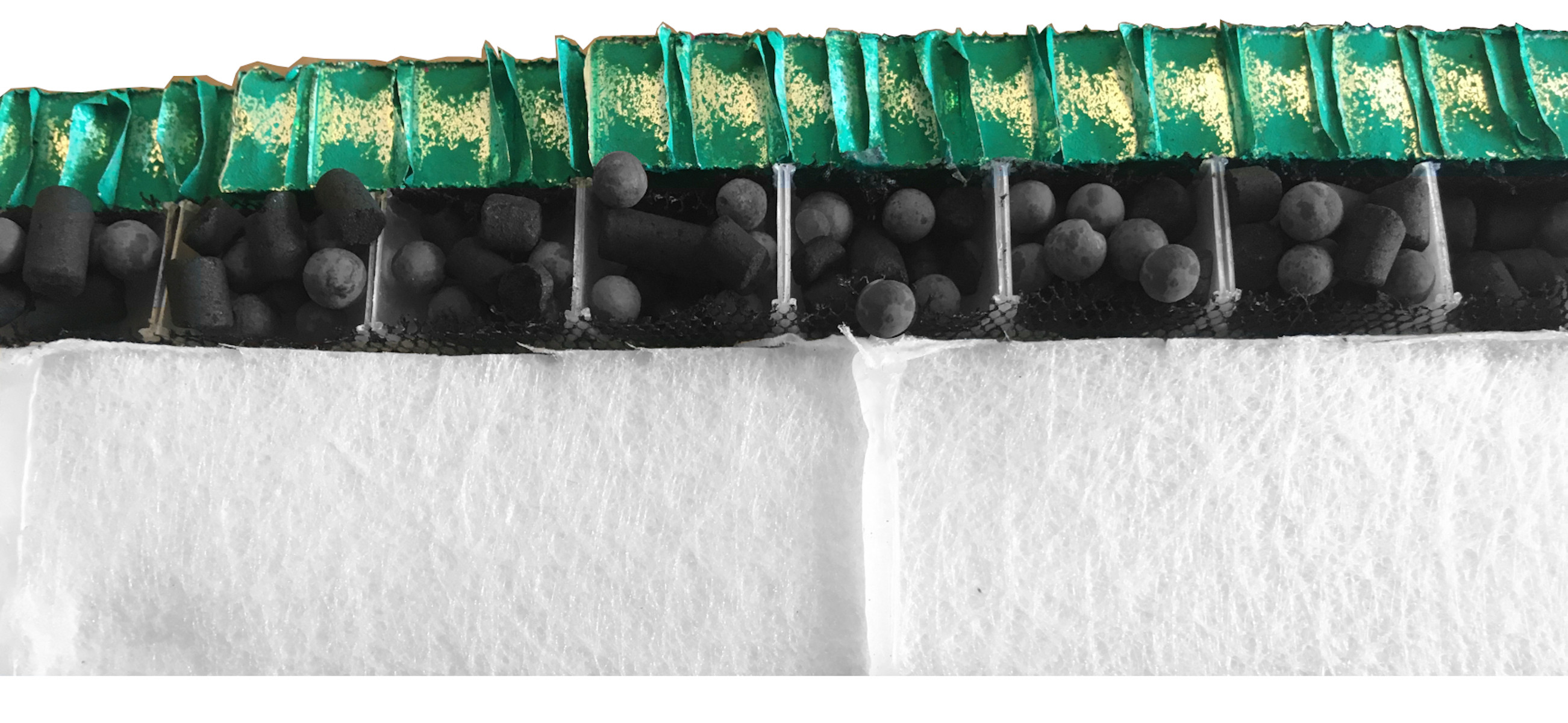 Geschichtetes Filtermaterial mit Aktivkohle, weißem Filter und grünen Kanten mit Gold.