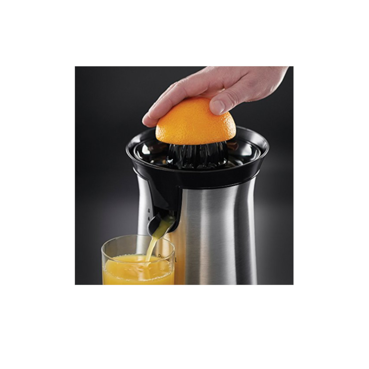 Una mano che spremi un'arancia su uno spremiagrumi, succo versato in un bicchiere.