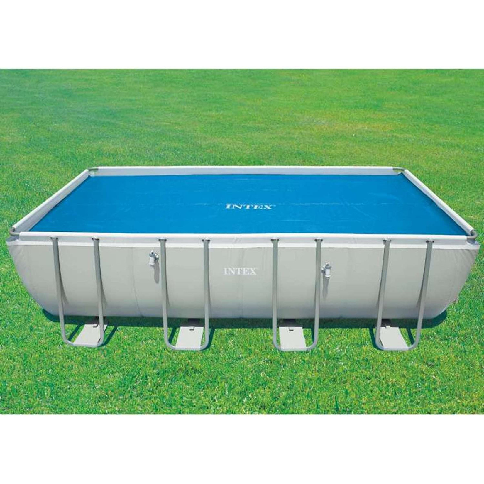 Rechteckiger, oberirdischer Swimmingpool mit blauer Abdeckung, auf grünem Gras.