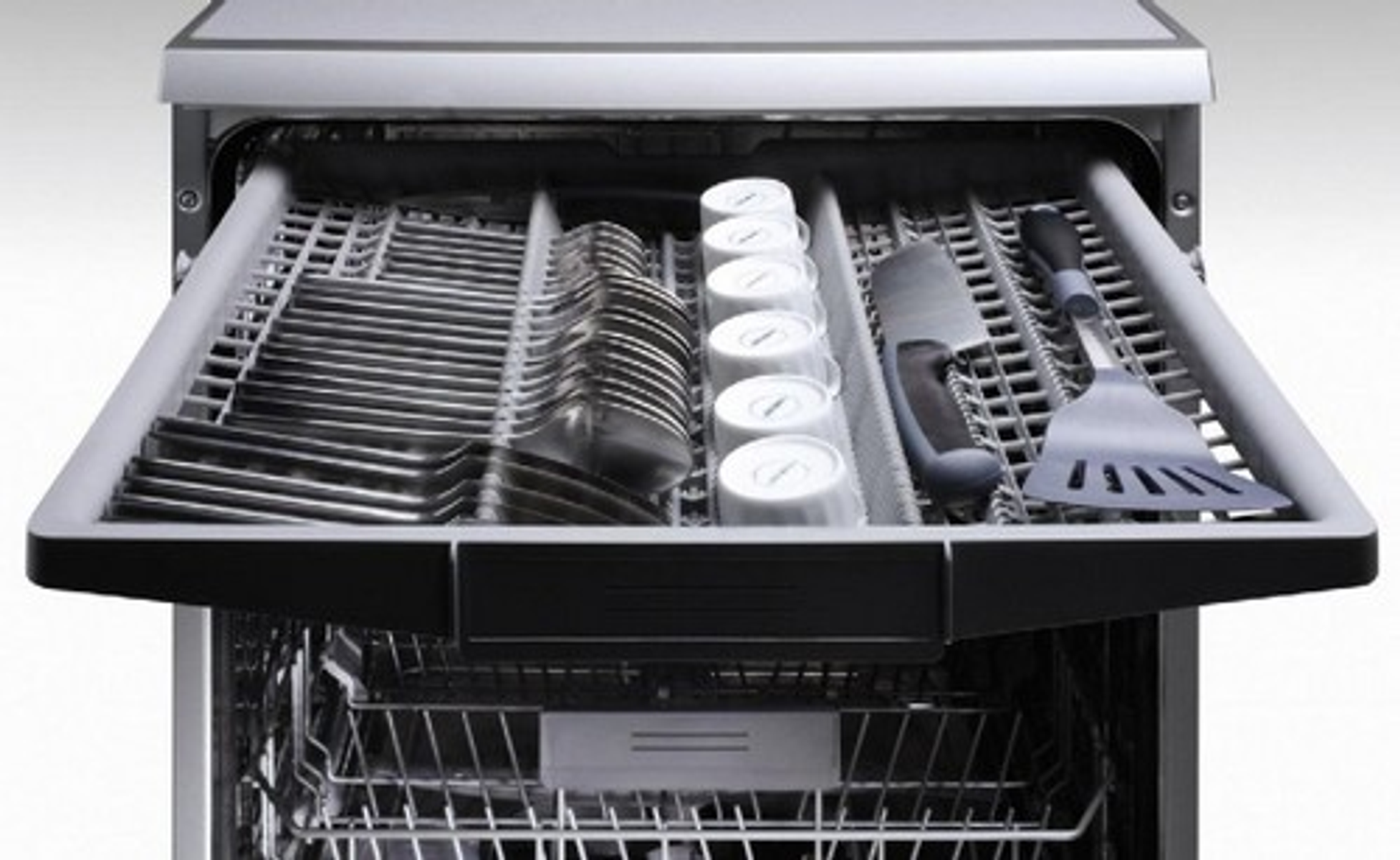 Wnętrze zmywarki otwarte, pokazujące sztućce, kubki i szpatułkę.