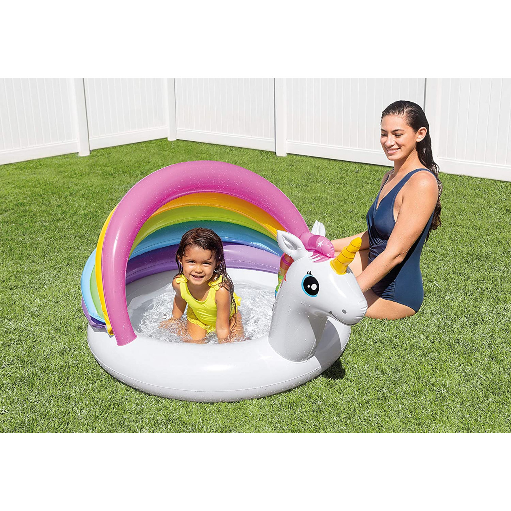 Ein Kind im gelben Badeanzug in einem Einhorn-Pool mit einer Frau im blauen Badeanzug.