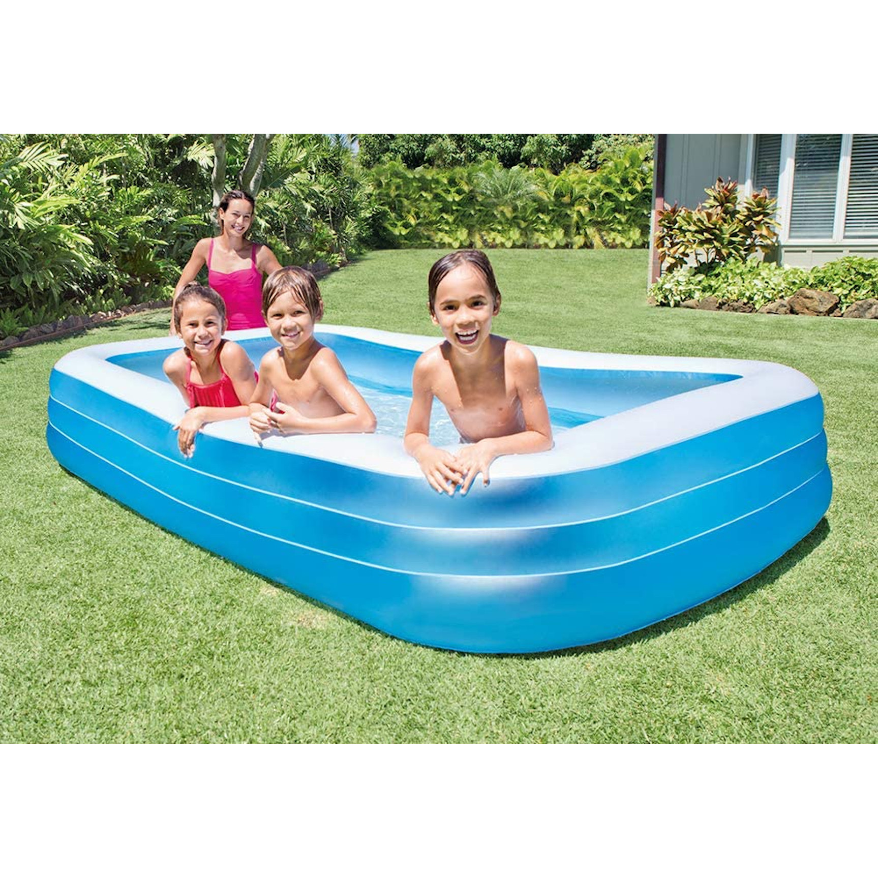 Vier Kinder und eine Frau in einem blau-weißen Pool in einem Garten.