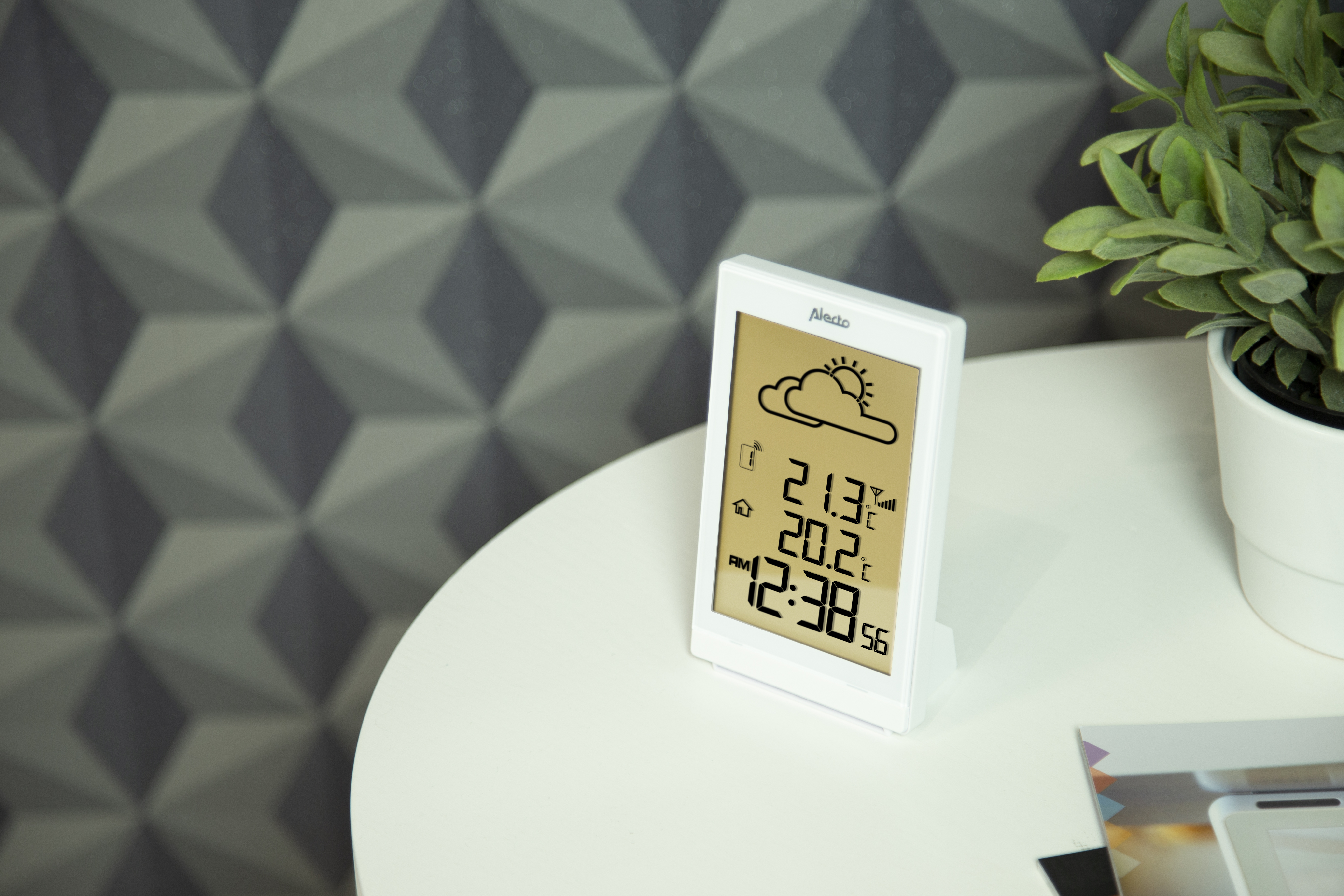Eine weiße digitale Wetterstation, die Temperatur und Zeit anzeigt, auf einem weißen Tisch.