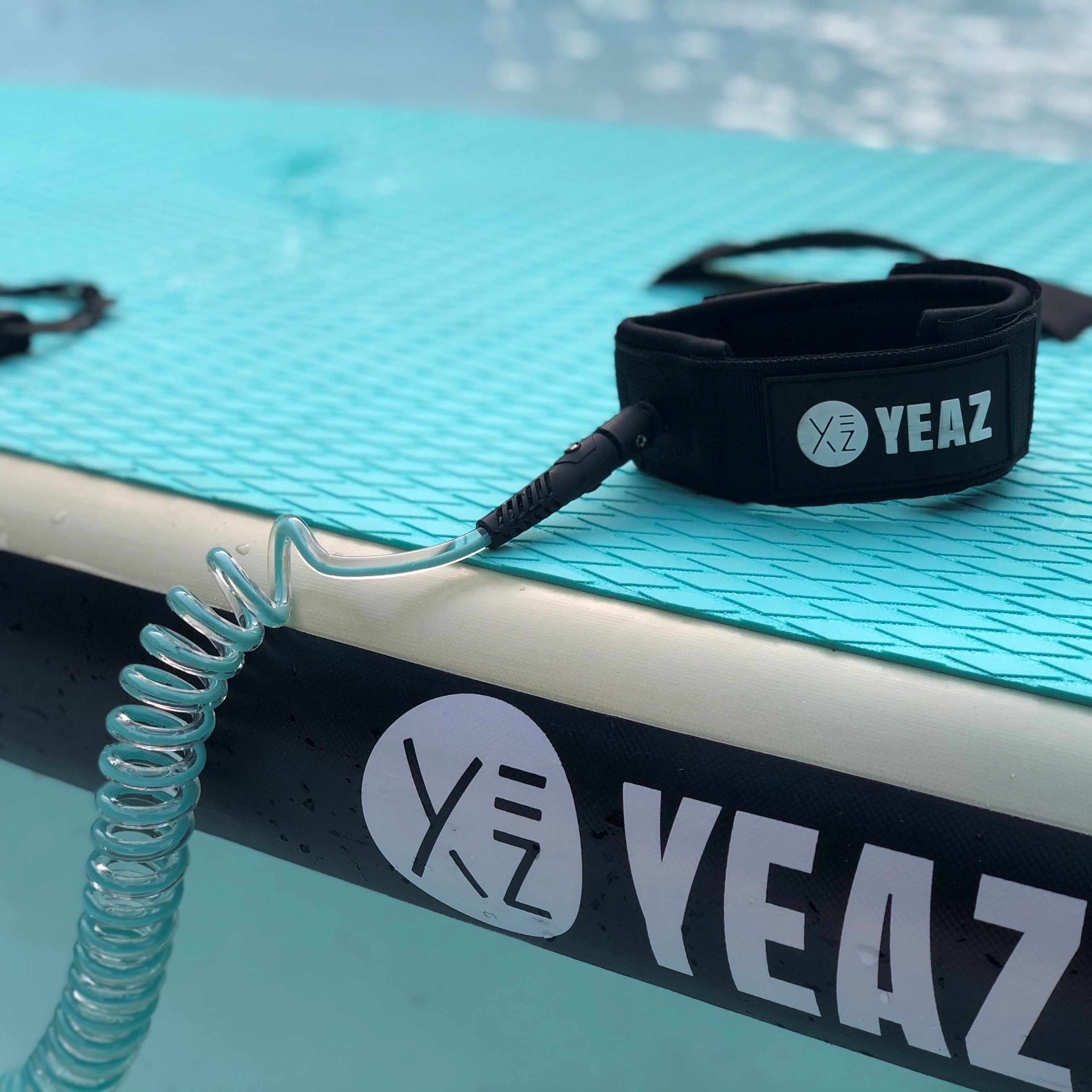 Blaues Paddleboard mit schwarzer Leine. 'YEAZ'-Logo auf der Leine und dem Board.