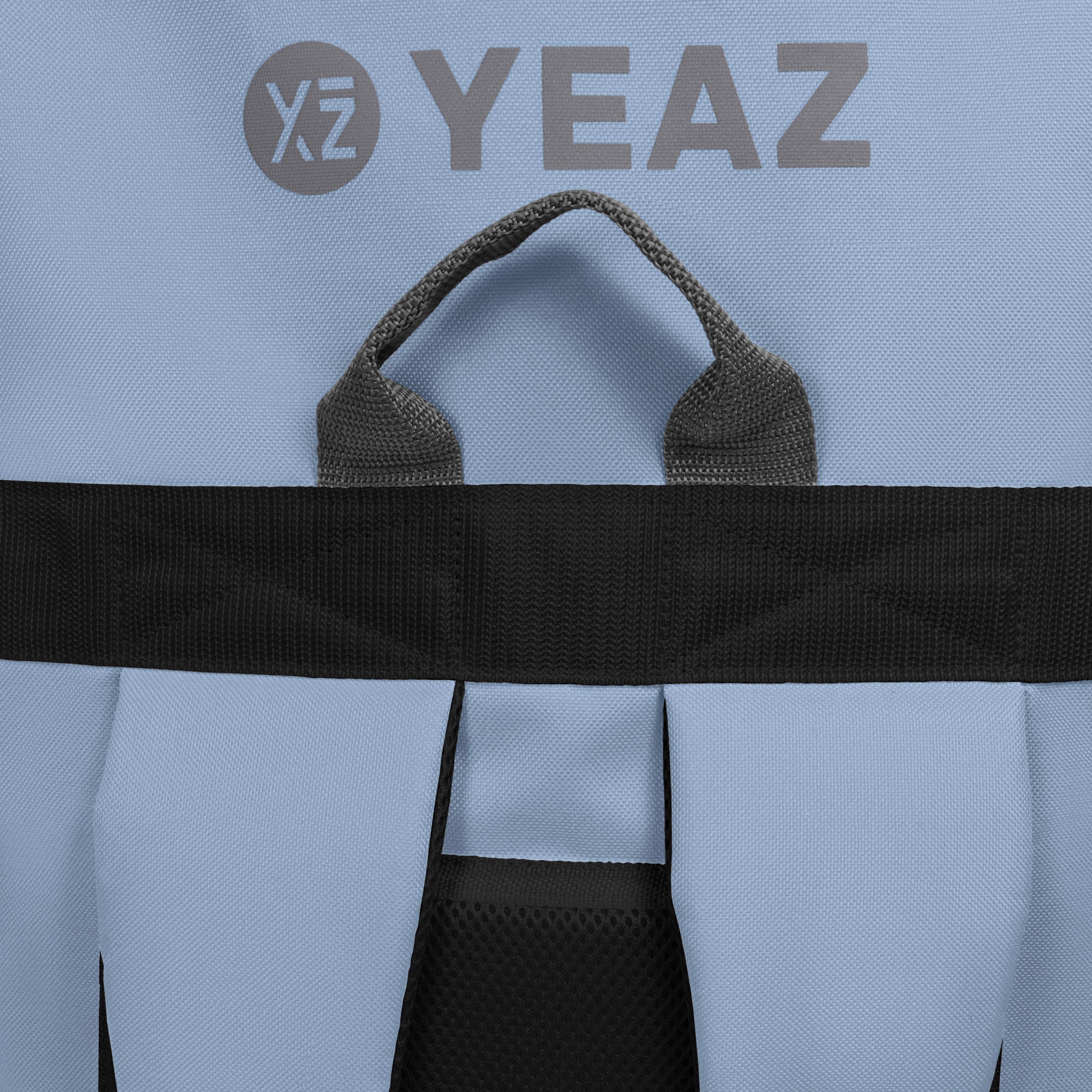 Rucksackdetail, hellblau mit schwarzem Riemen, grauem Griff und YEAZ-Logo.