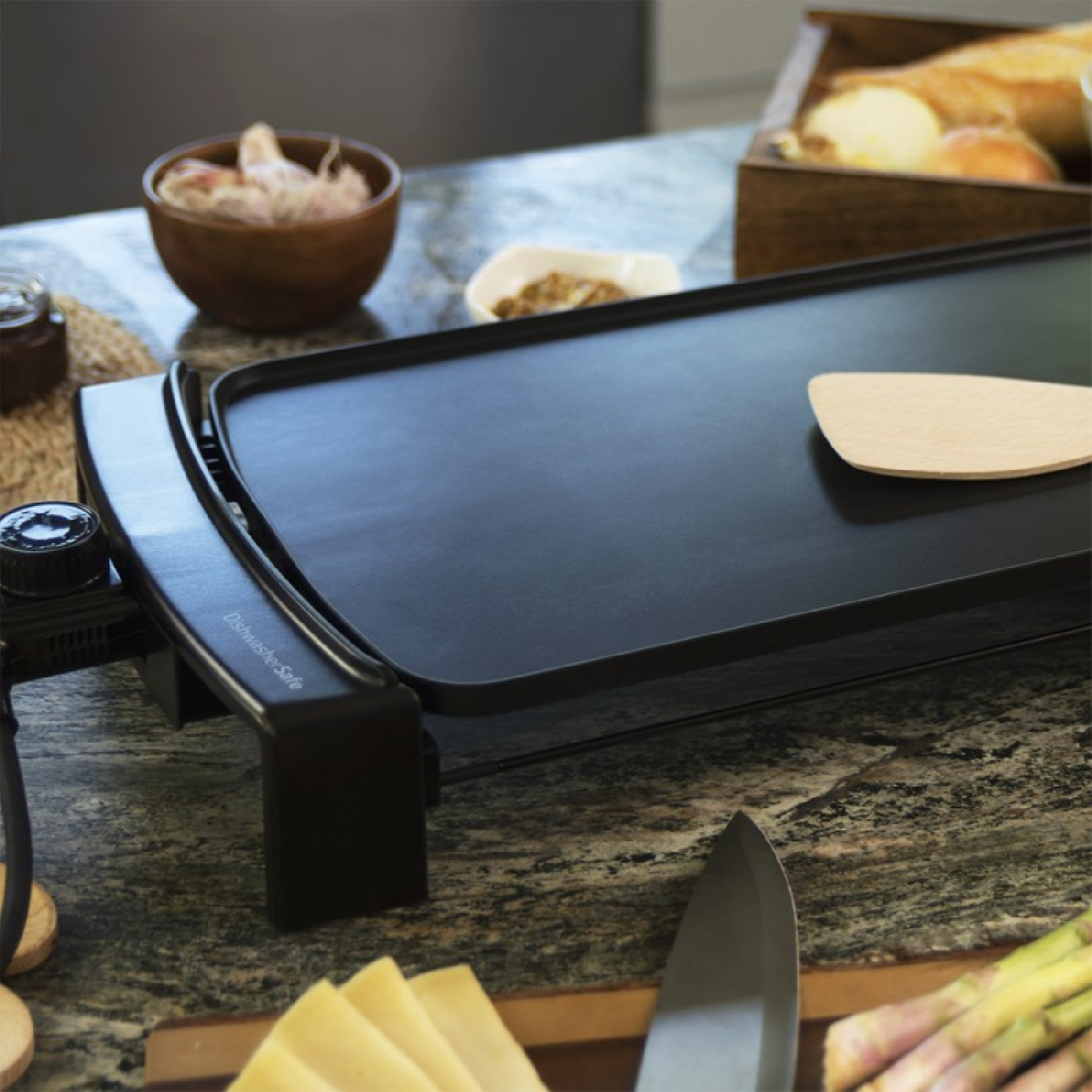 Una piastra nera con una spatola di legno e alimenti.