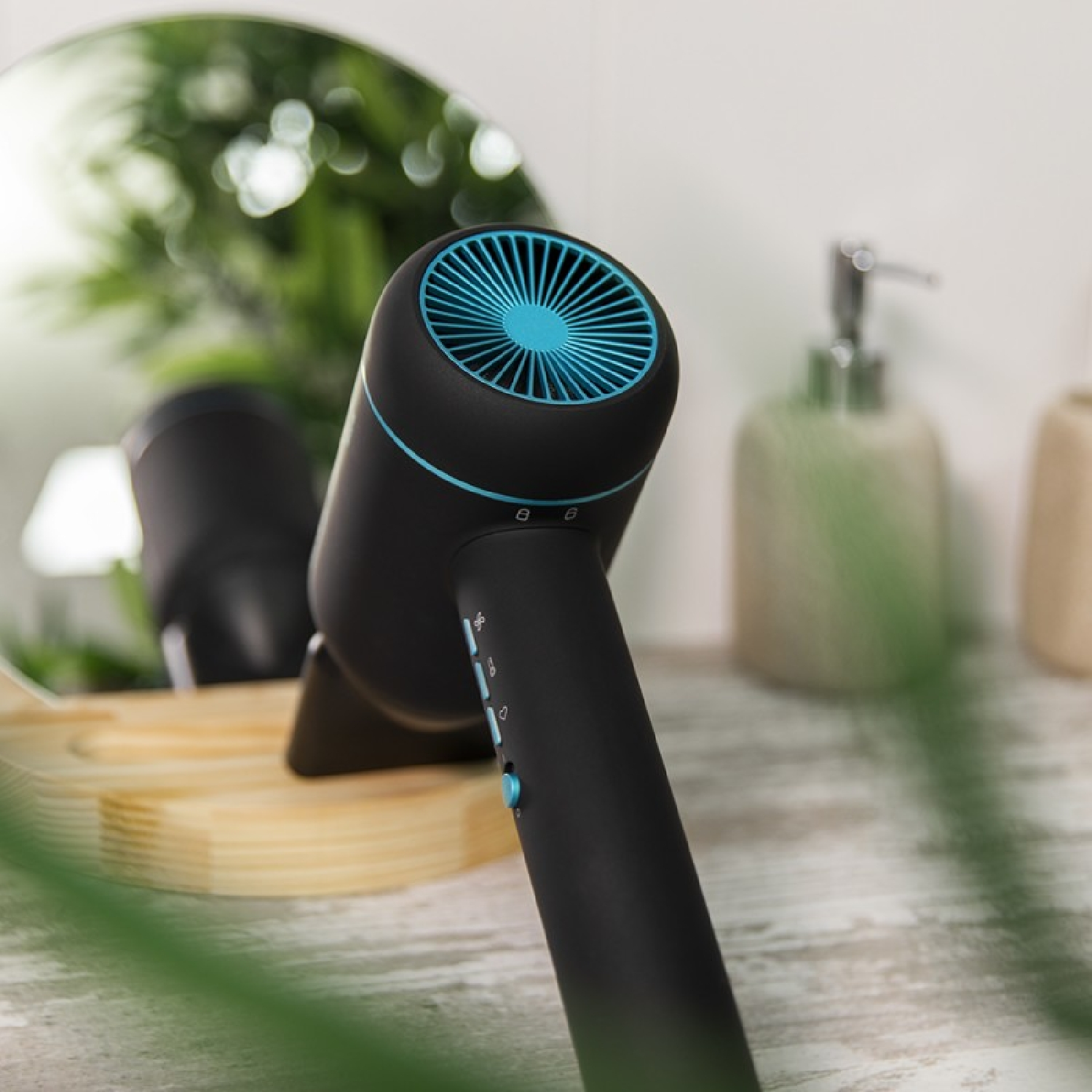 Asciugacapelli nero e blu. È su un supporto in legno davanti a uno specchio e altri oggetti da bagno.
