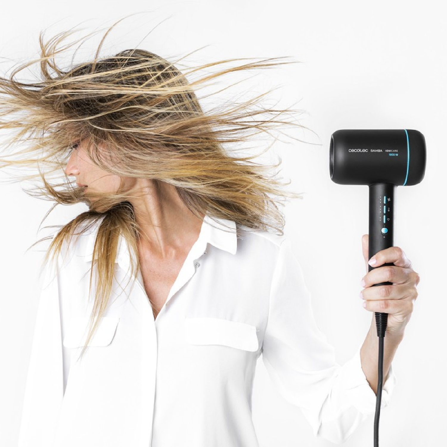 Una donna che tiene un asciugacapelli nero, con i capelli al vento.