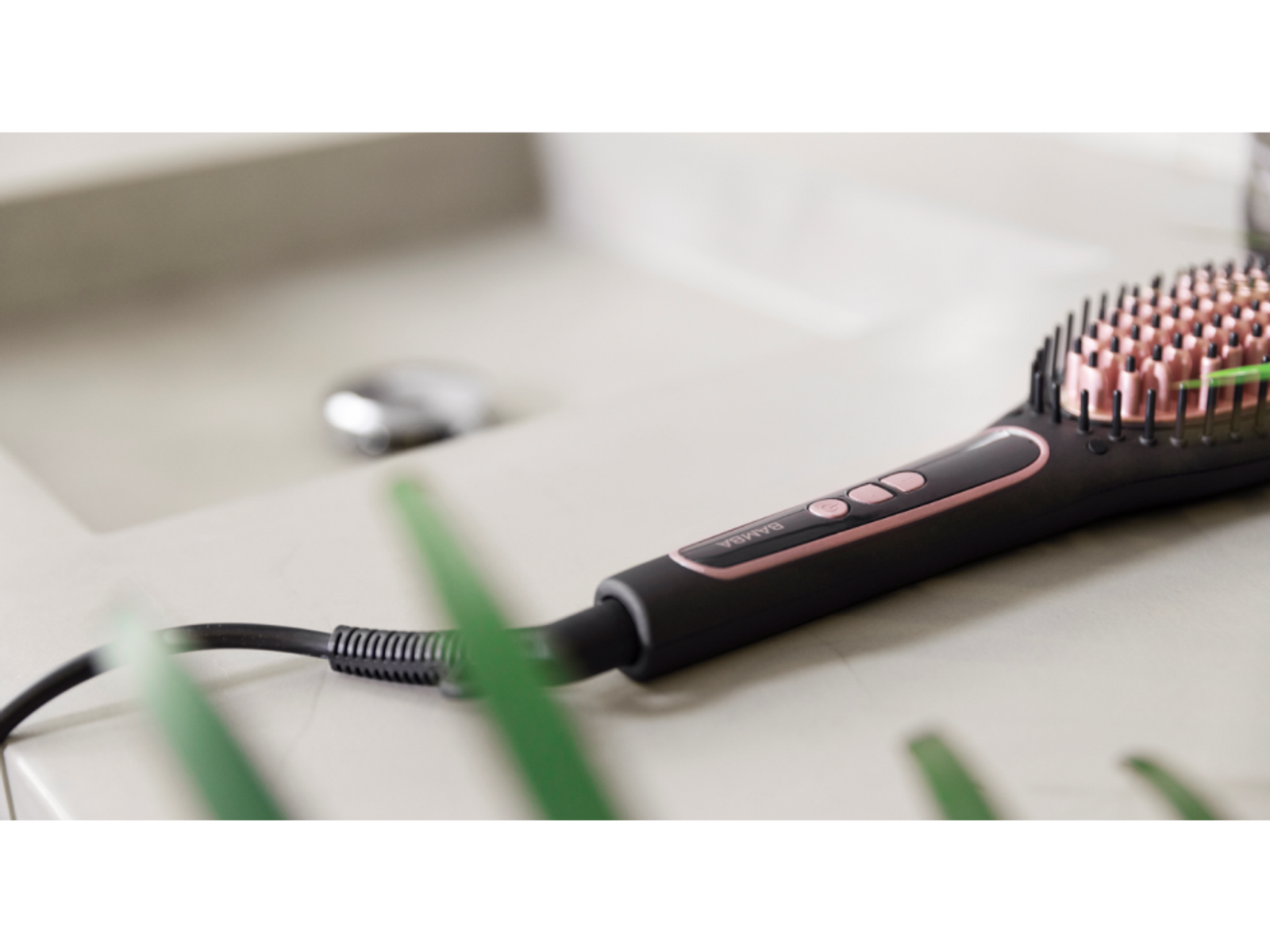 Een zwarte en roze haarstylingborstel op een badkamerblad.