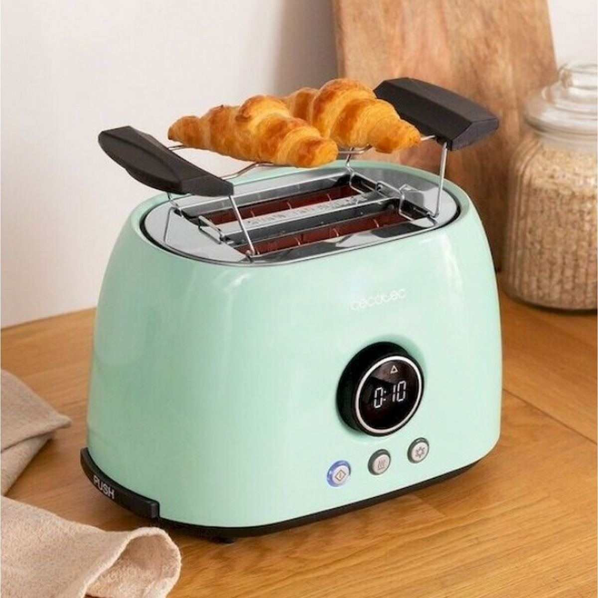 Miętowy toster z dwoma rogalikami. Wyświetlacz cyfrowy pokazuje czas.