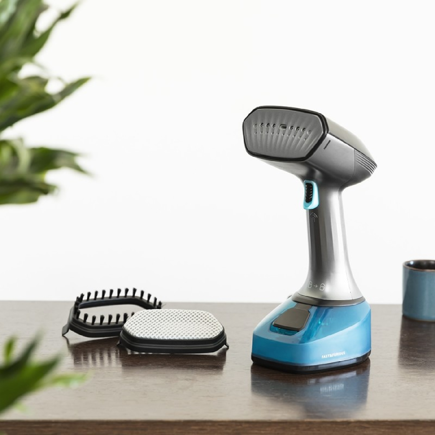 Vaporizzatore per indumenti portatile e accessori su un tavolo di legno. Sfondo bianco.