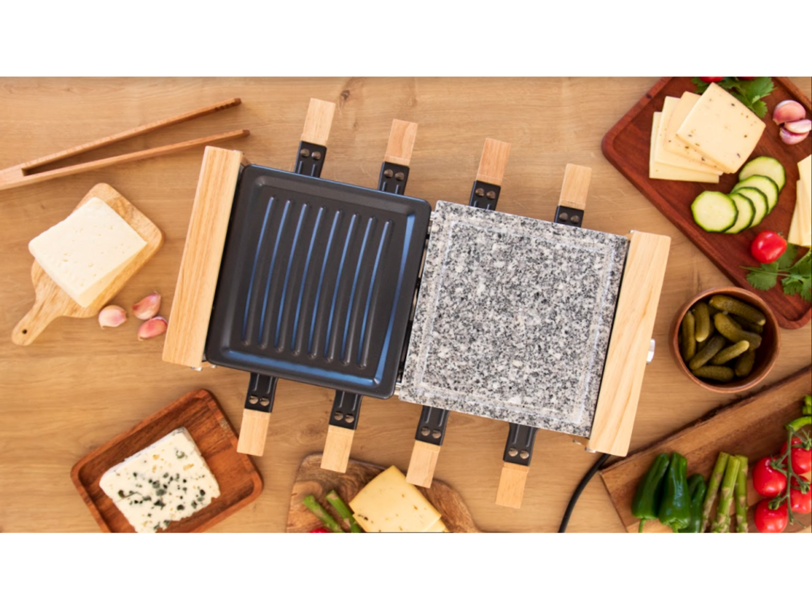 Grill do raclette i składniki na drewnianej powierzchni: ser, warzywa i ogórki kiszone. Widok z góry.