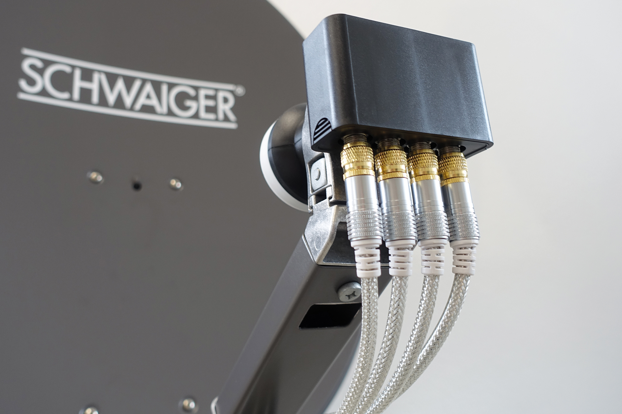 Zbliżenie czarnego urządzenia ze srebrnymi i złotymi złączami. Tekst: SCHWAIGER. Kable i złącza w ostrości.