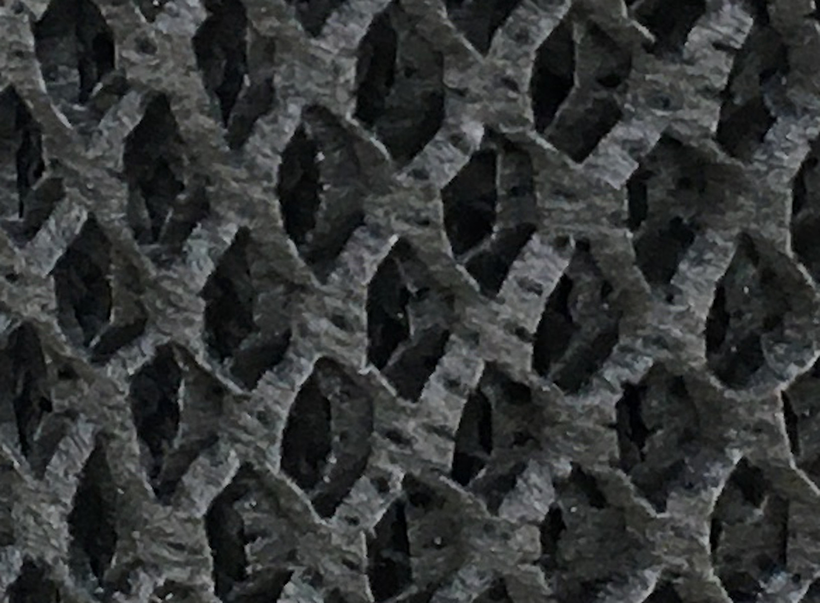Nahaufnahme eines schwarzen, netzartigen Materials mit Rautenmuster.