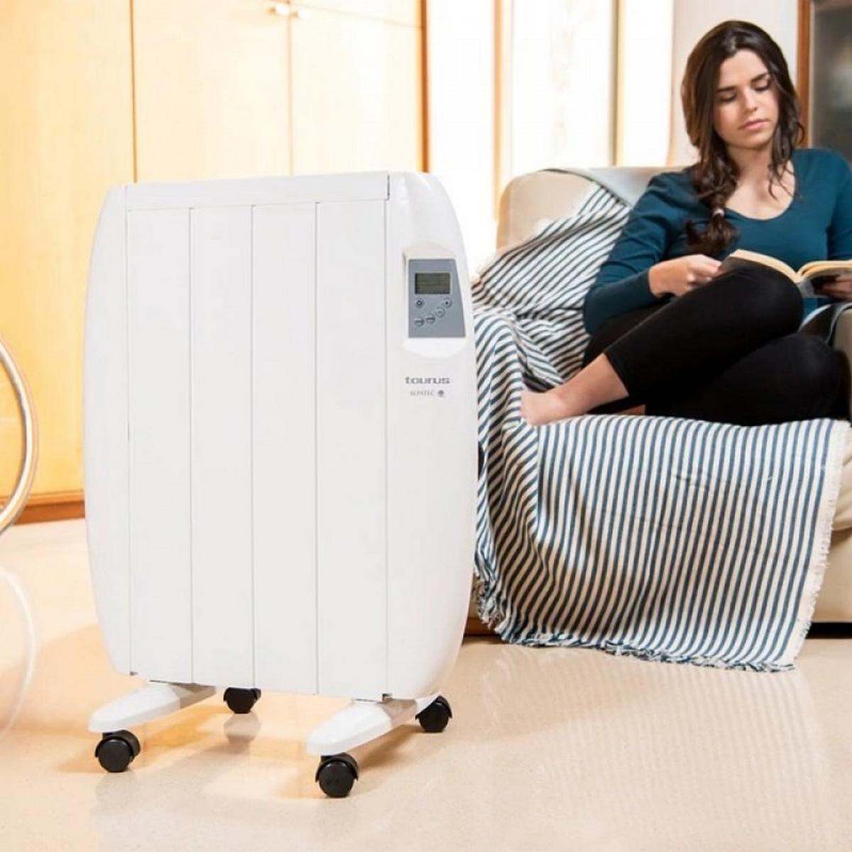 Eine Frau liest neben einem weißen Elektroheizer mit Digitalanzeige, auf Rädern.