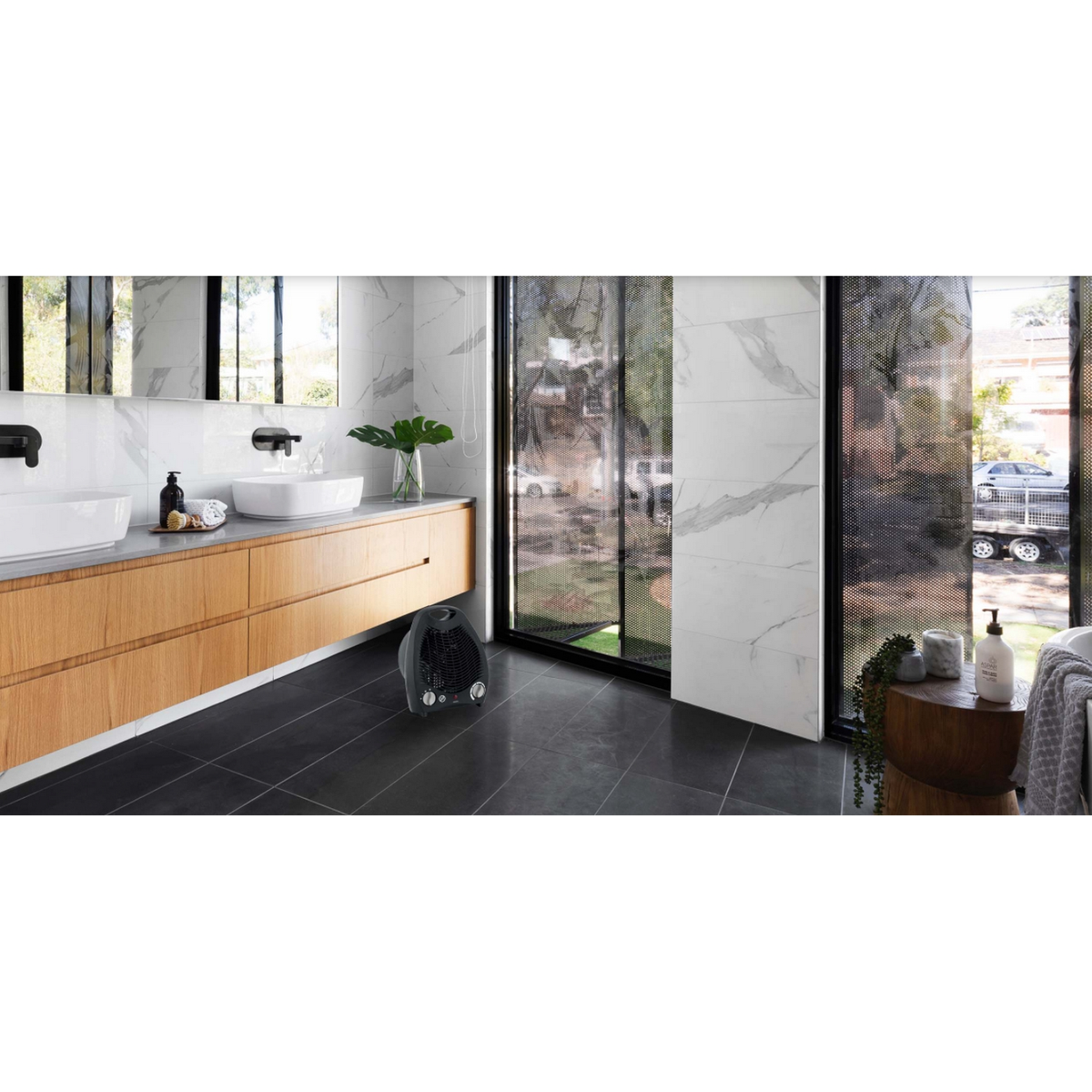 Baño moderno con calefactor negro. La habitación tiene paredes blancas y baldosas oscuras.