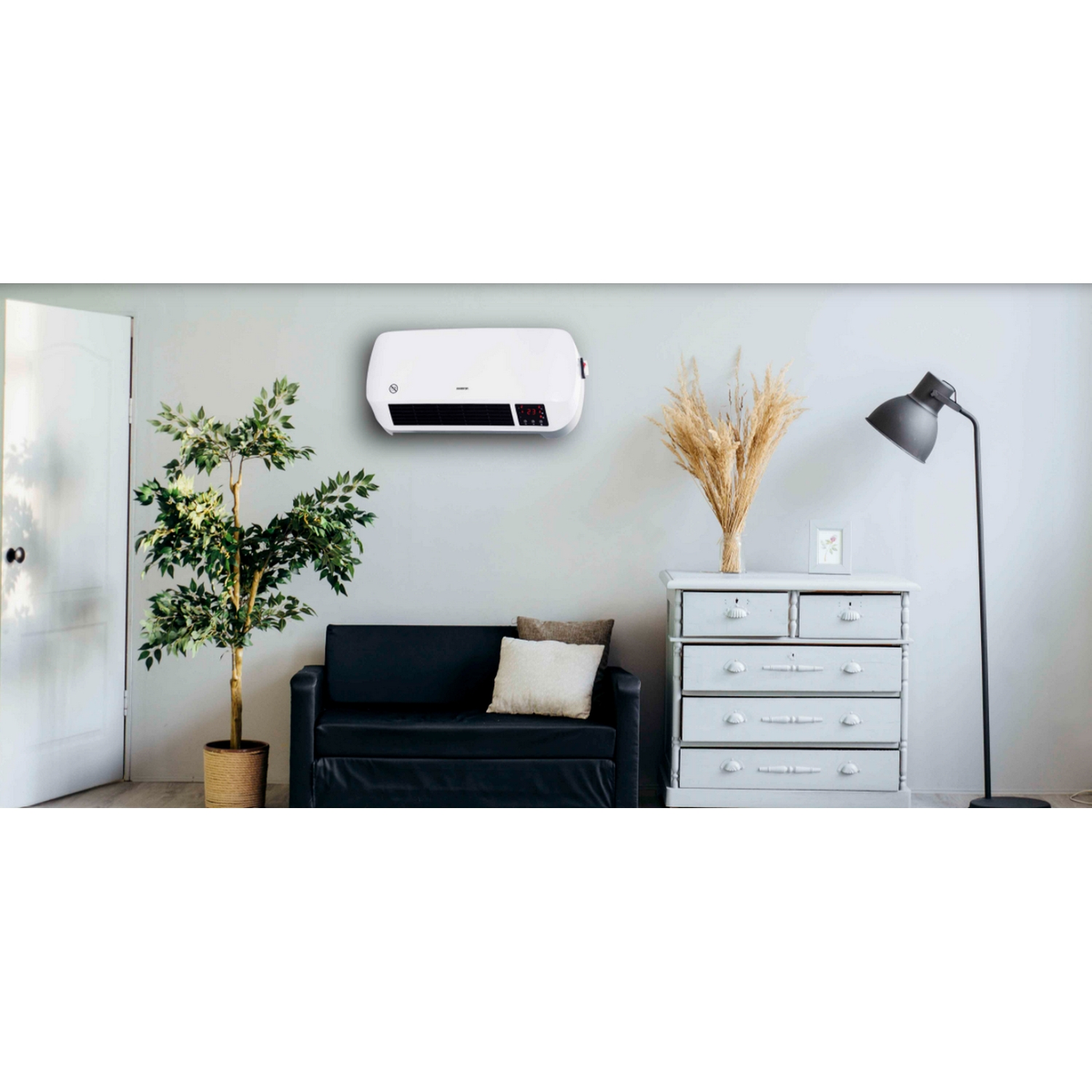 Calefactor de pared blanco, sofá negro, planta, cómoda y lámpara.