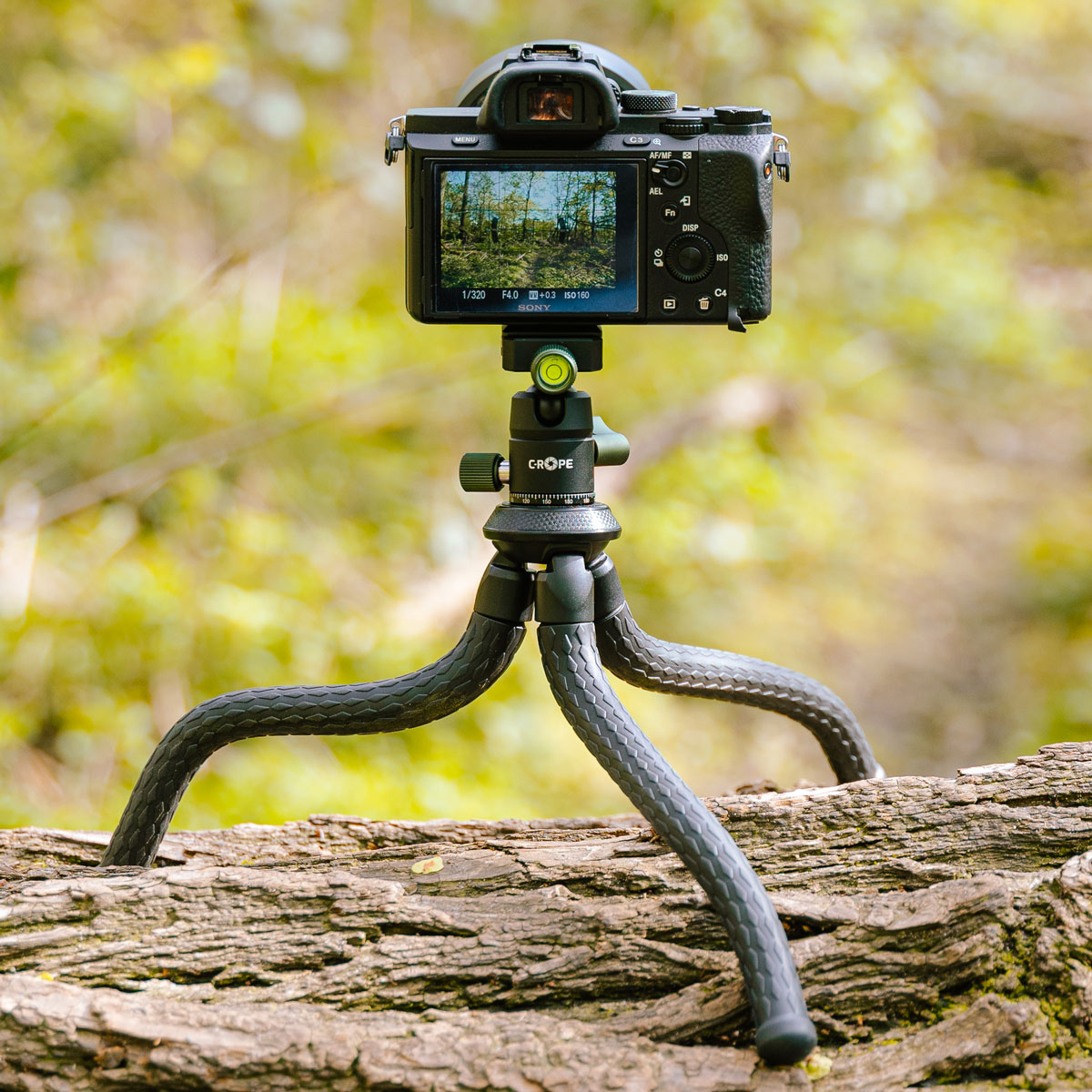 Czarny aparat na elastycznym statywie w lesie.