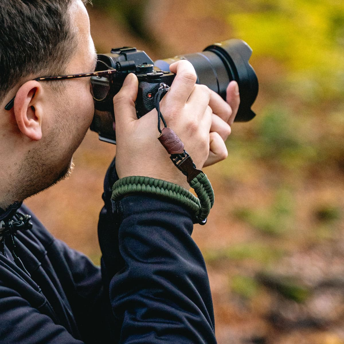 Una persona tiene in mano una macchina fotografica e scatta una foto, con un cinturino da polso.