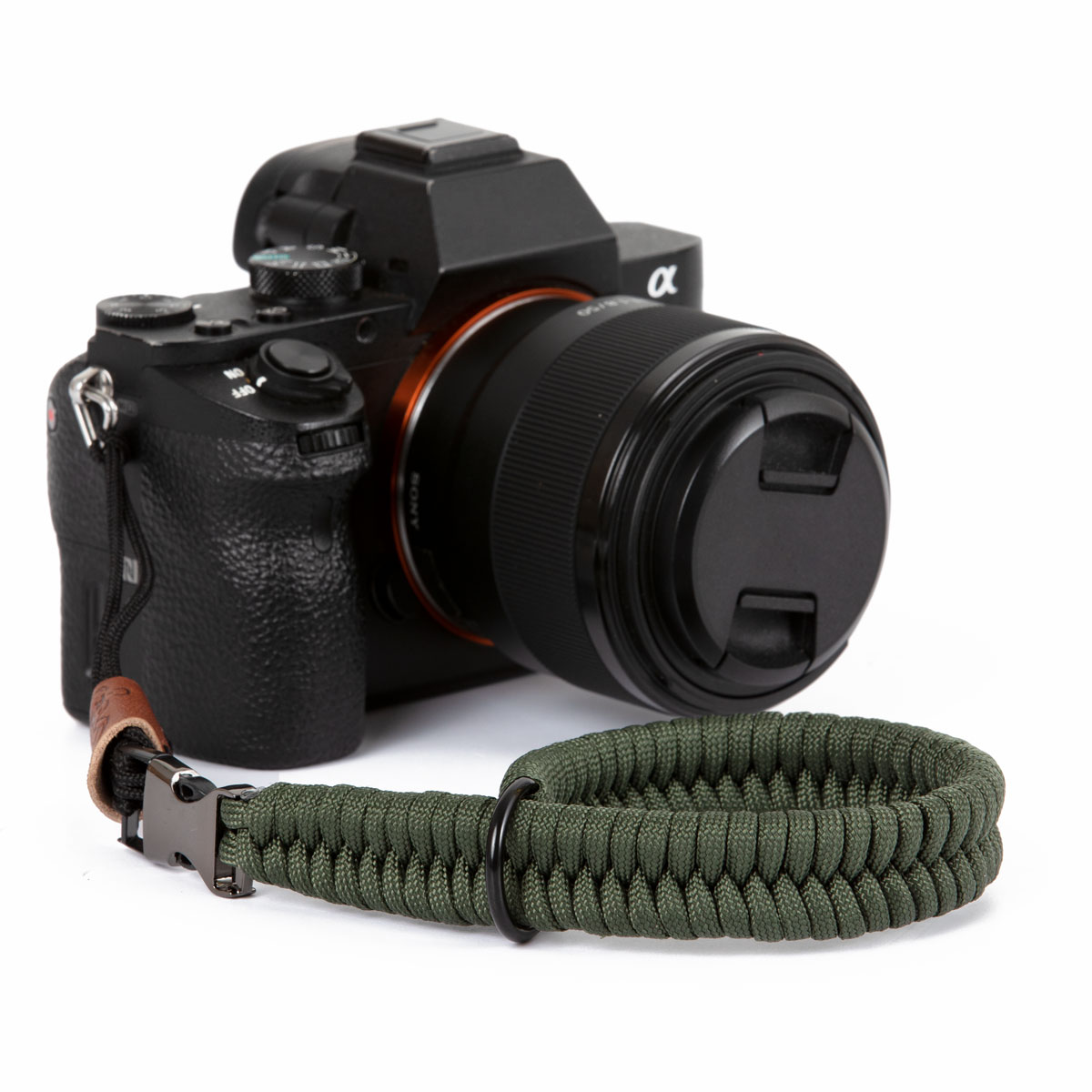 Fotocamera nera con cinturino da polso verde. Dettagli in pelle e metallo.