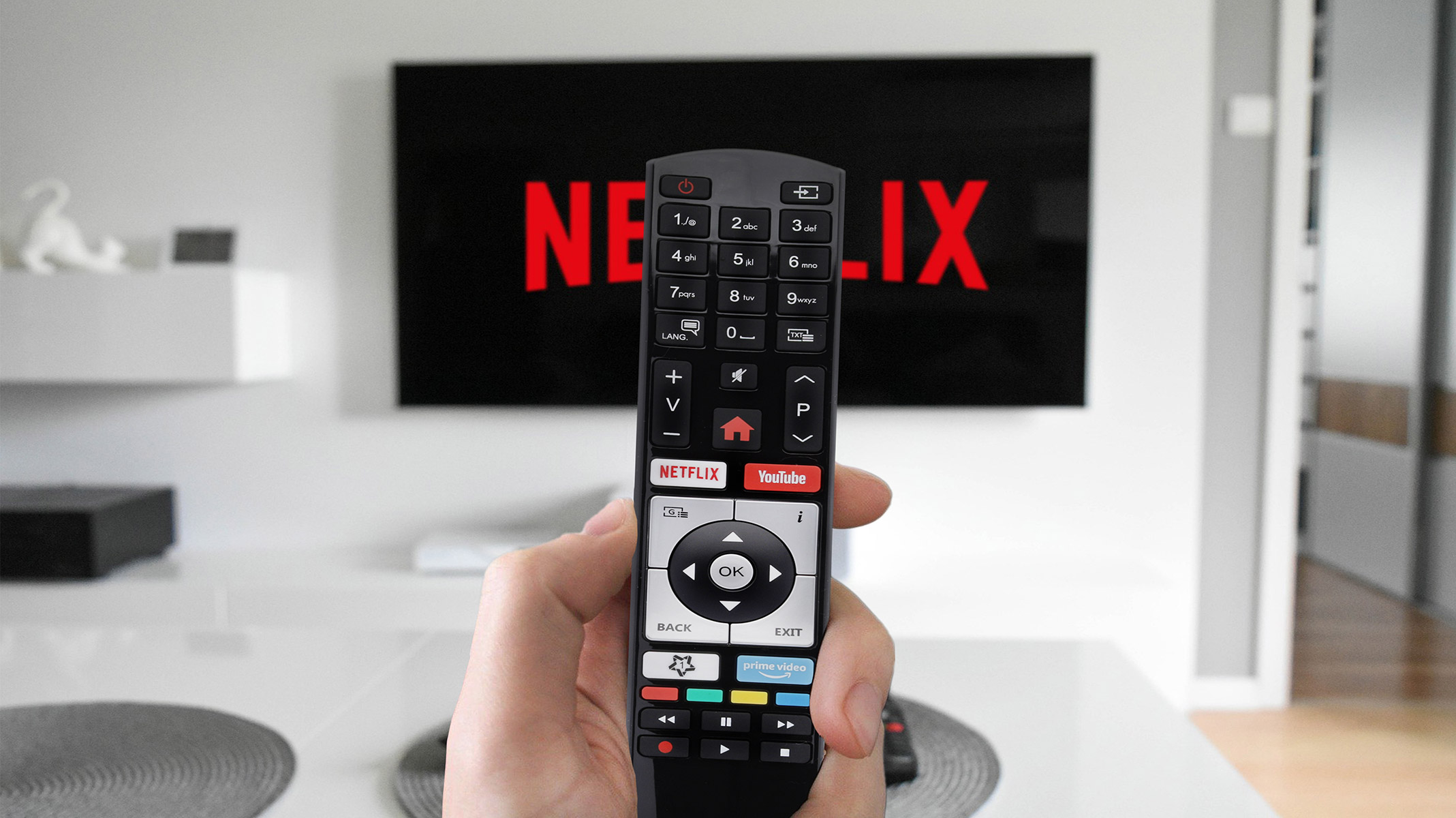 Eine Person hält eine Fernbedienung vor einem Fernsehbildschirm mit Netflix-Logo.