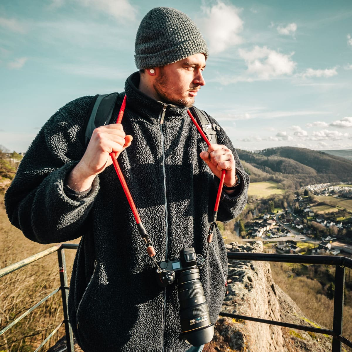 Mann mit Jacke, Kamera um den Hals, Blick auf Landschaft.