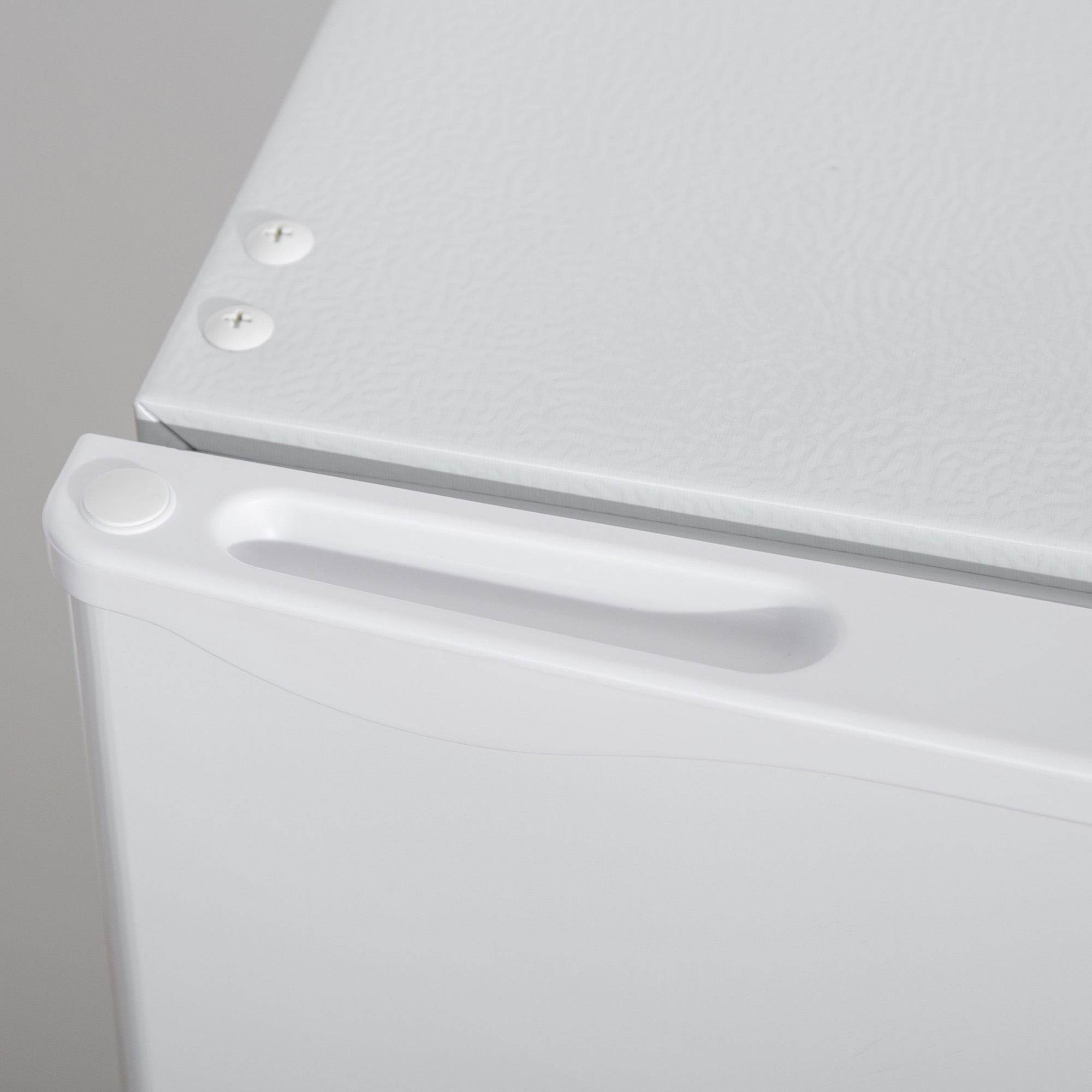 Primo piano di un frigorifero bianco. Mostra la maniglia superiore e la parte superiore della porta.