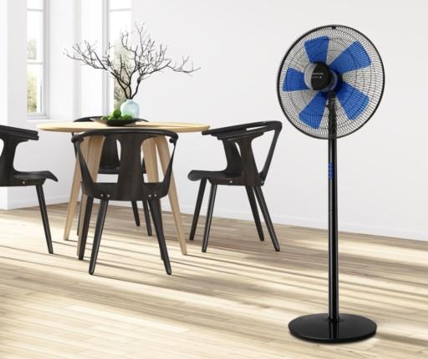 Pokój ze stołem i krzesłami oraz wentylatorem stojącym. Wentylator ma niebieskie łopatki.