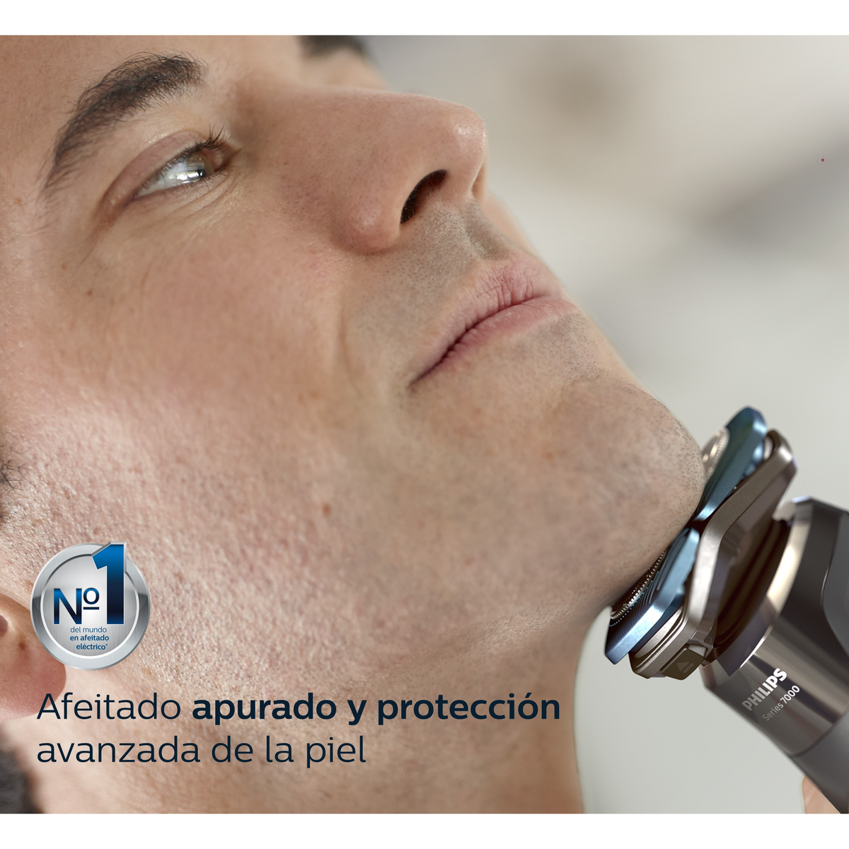 Un hombre se afeita con una afeitadora eléctrica. La afeitadora es gris y negra. Texto: 'Afeitado apurado y protección'.