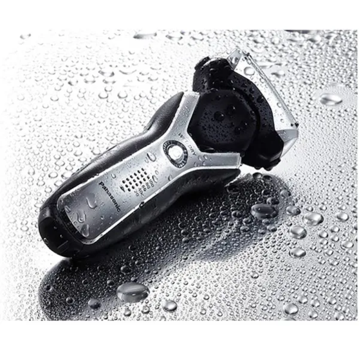 Golarka elektryczna na mokrej powierzchni z kroplami wody. Golarka czarno-srebrna, marki Panasonic.