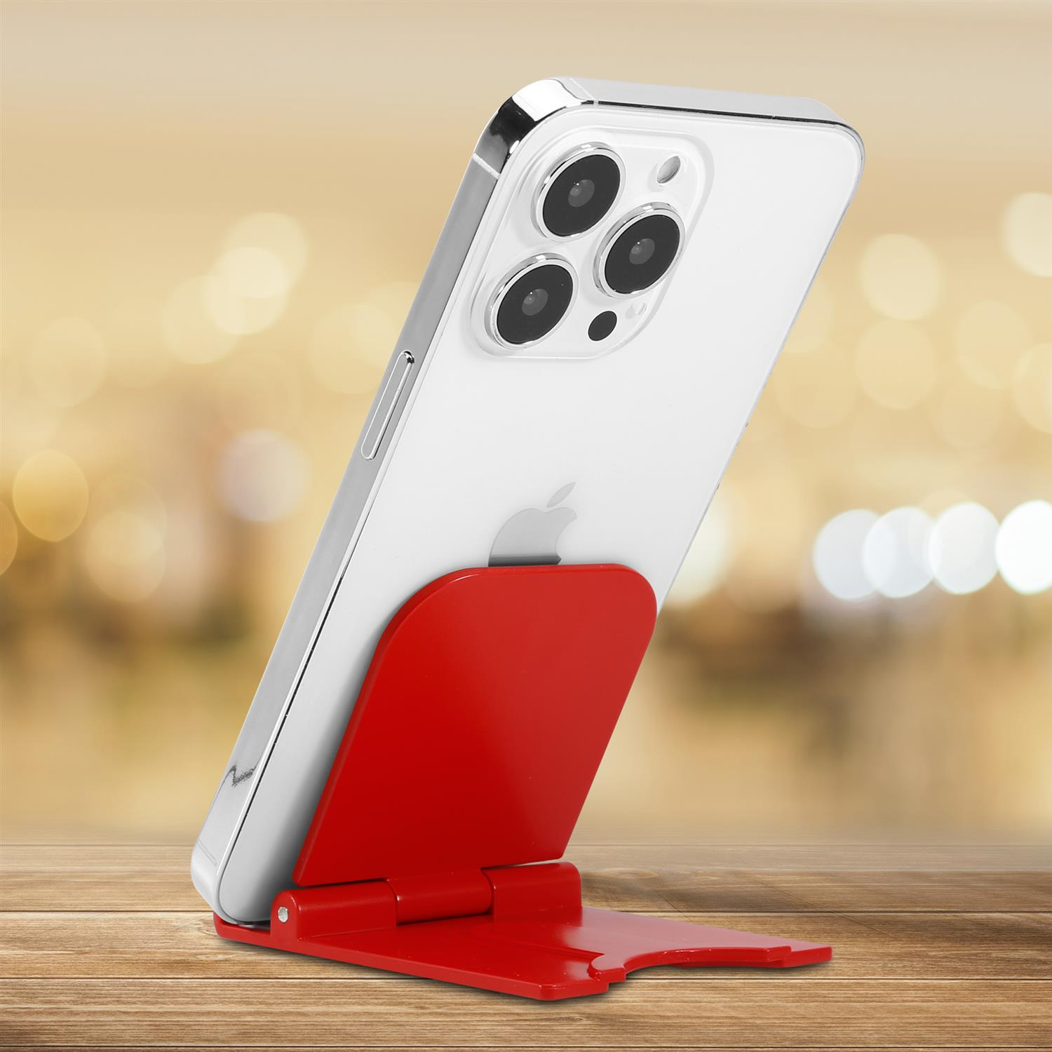 Weißes Smartphone auf rotem Ständer vor verschwommenem Hintergrund mit Bokeh-Lichtern.