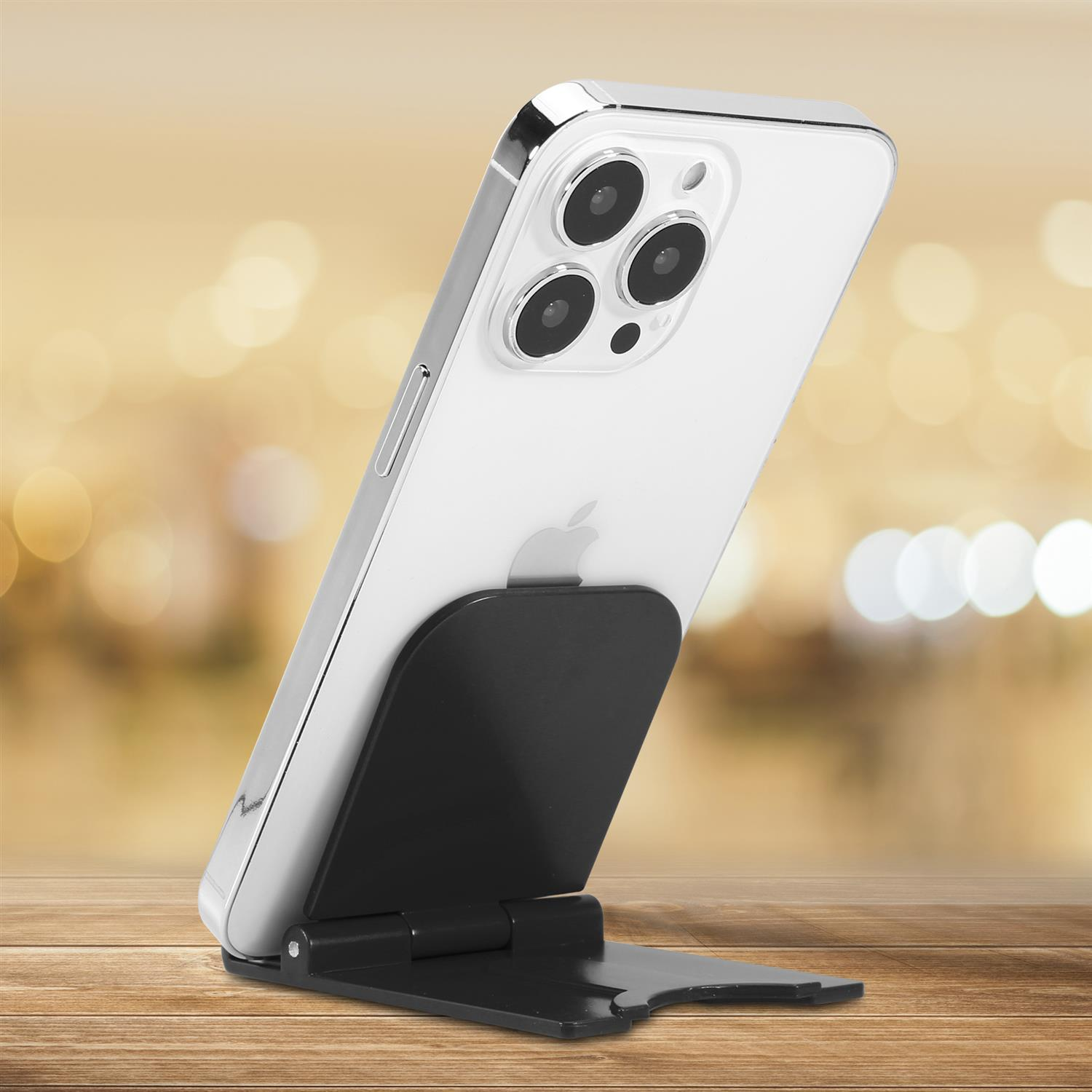 Ein weißes Smartphone auf einem schwarzen Ständer, platziert auf einem Holztisch.
