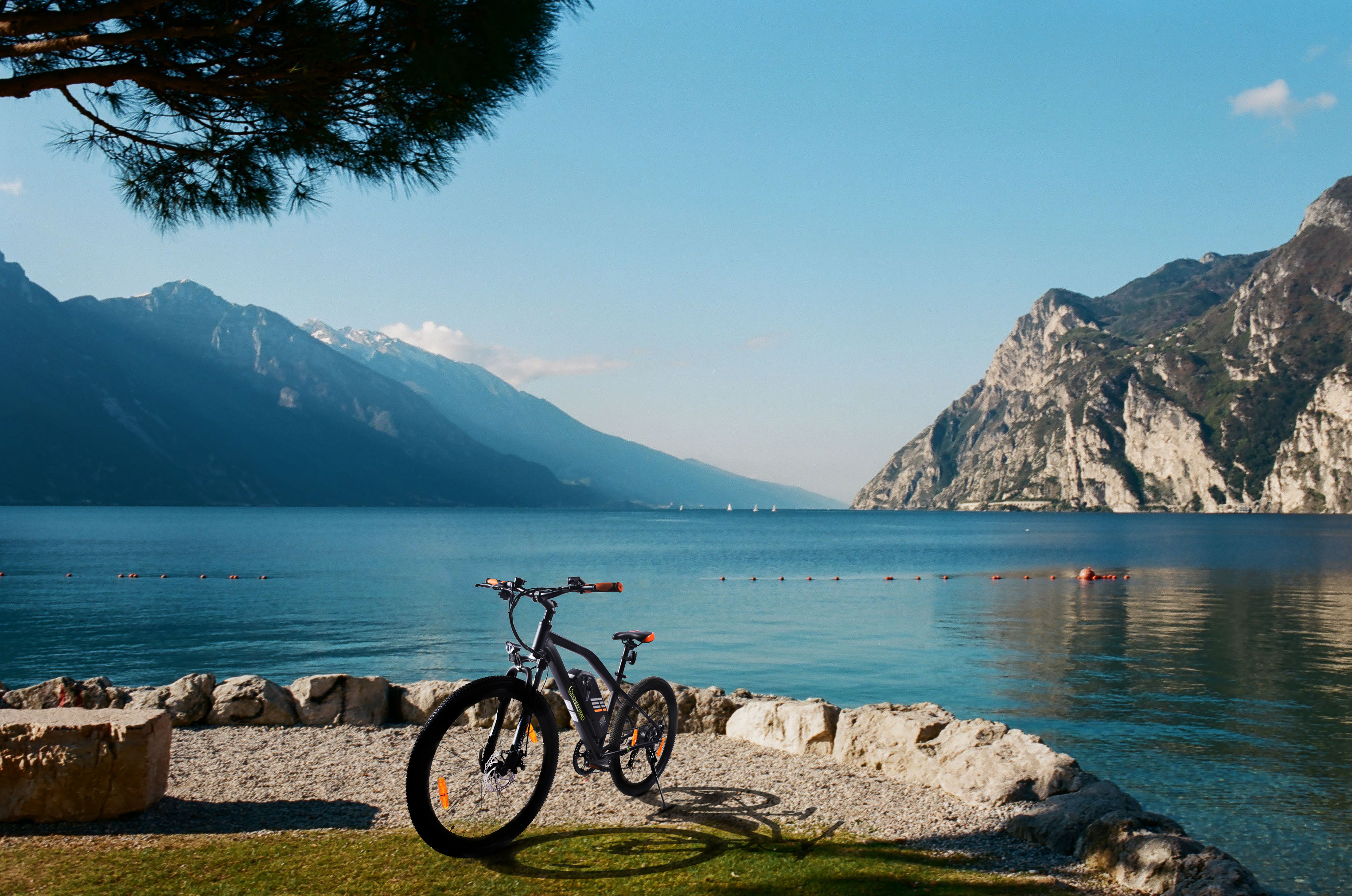 Ein Fahrrad steht in der Nähe eines Sees mit Bergen im Hintergrund unter blauem Himmel.