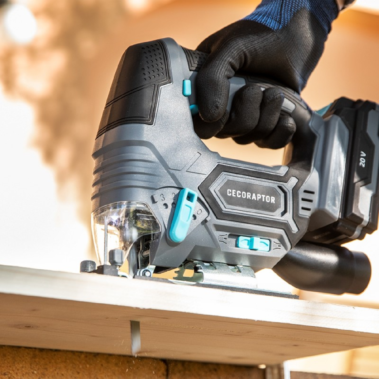 Szara i czarna wyrzynarka tnie białą deskę ręką w rękawicy. Tło jest rozmyte.