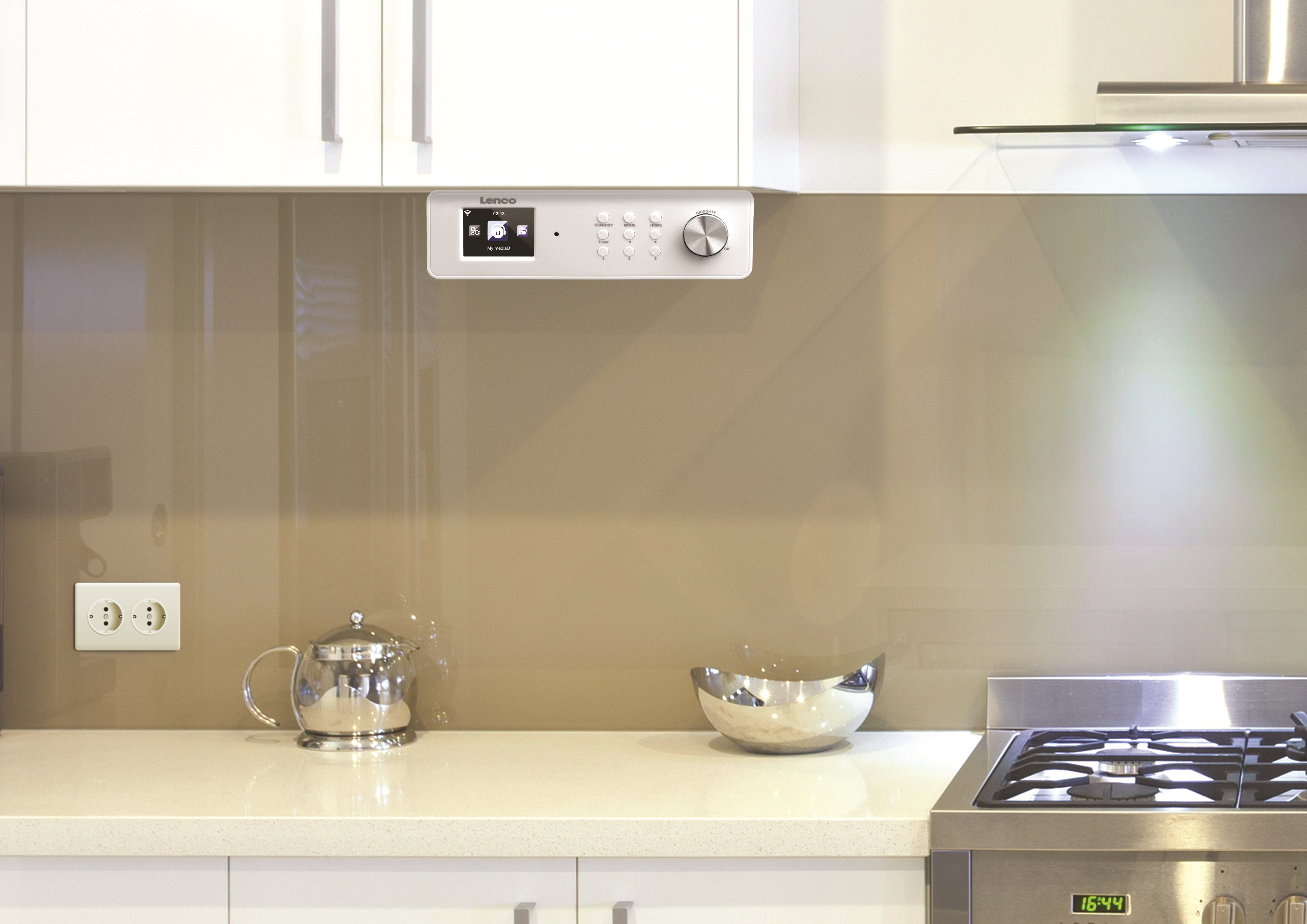 A kitchen scene. A radio is mounted on the wall and a kettle on the counter.