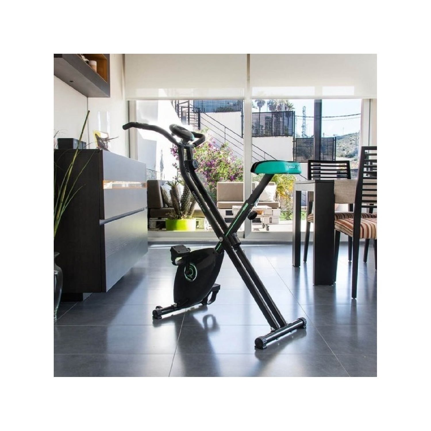 Bicicleta estática negra y verde. En una cocina. Fondo interior.