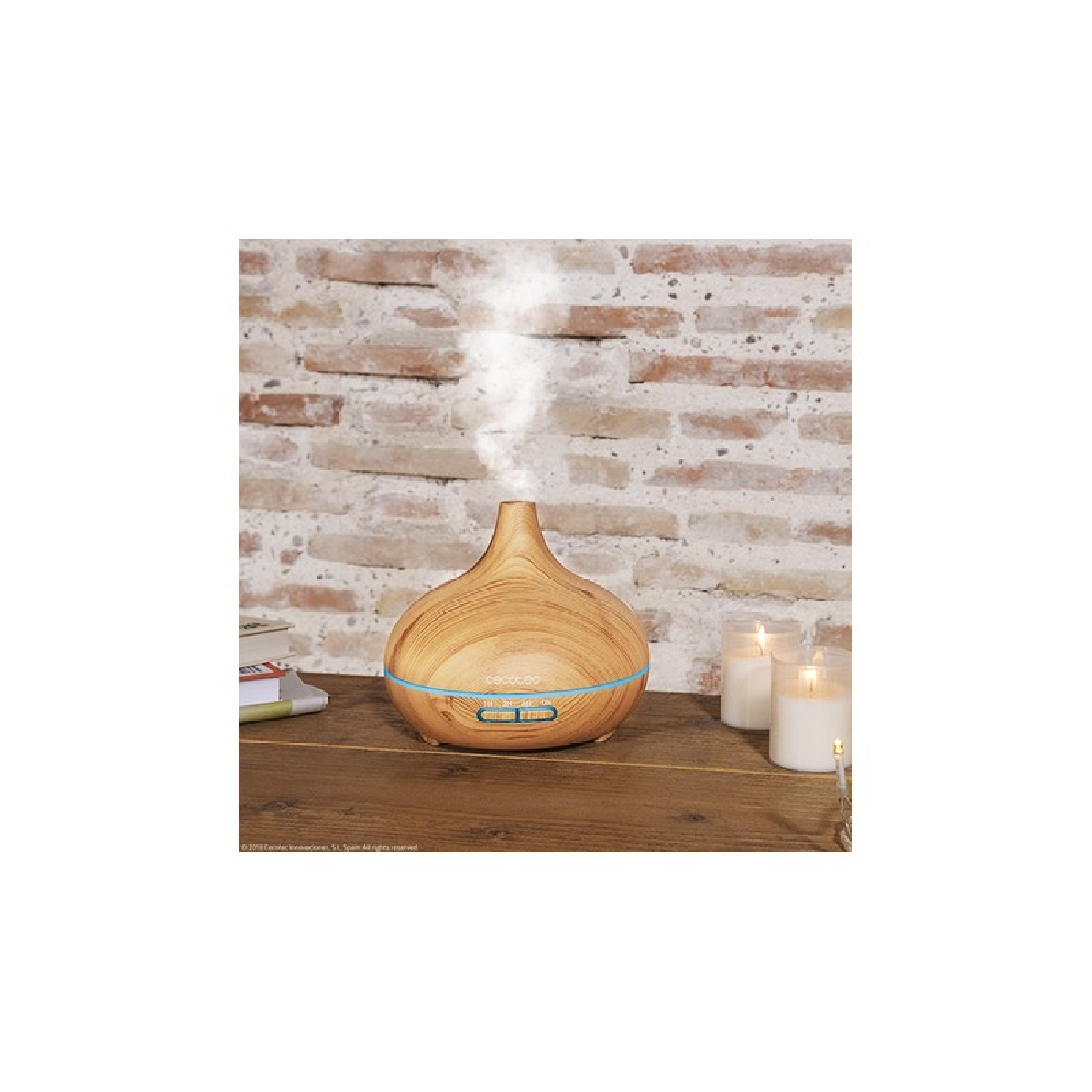 Diffusore di aromi in legno con nebbia che ne esce. Candele e libri sono sul tavolo.