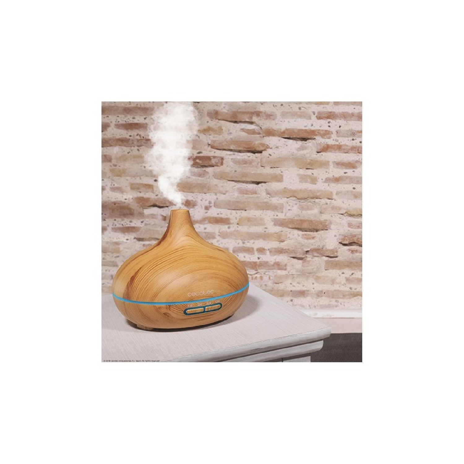 Diffusore di aromi in legno con vapore che sale. È posto su un tavolo bianco contro un muro di mattoni.